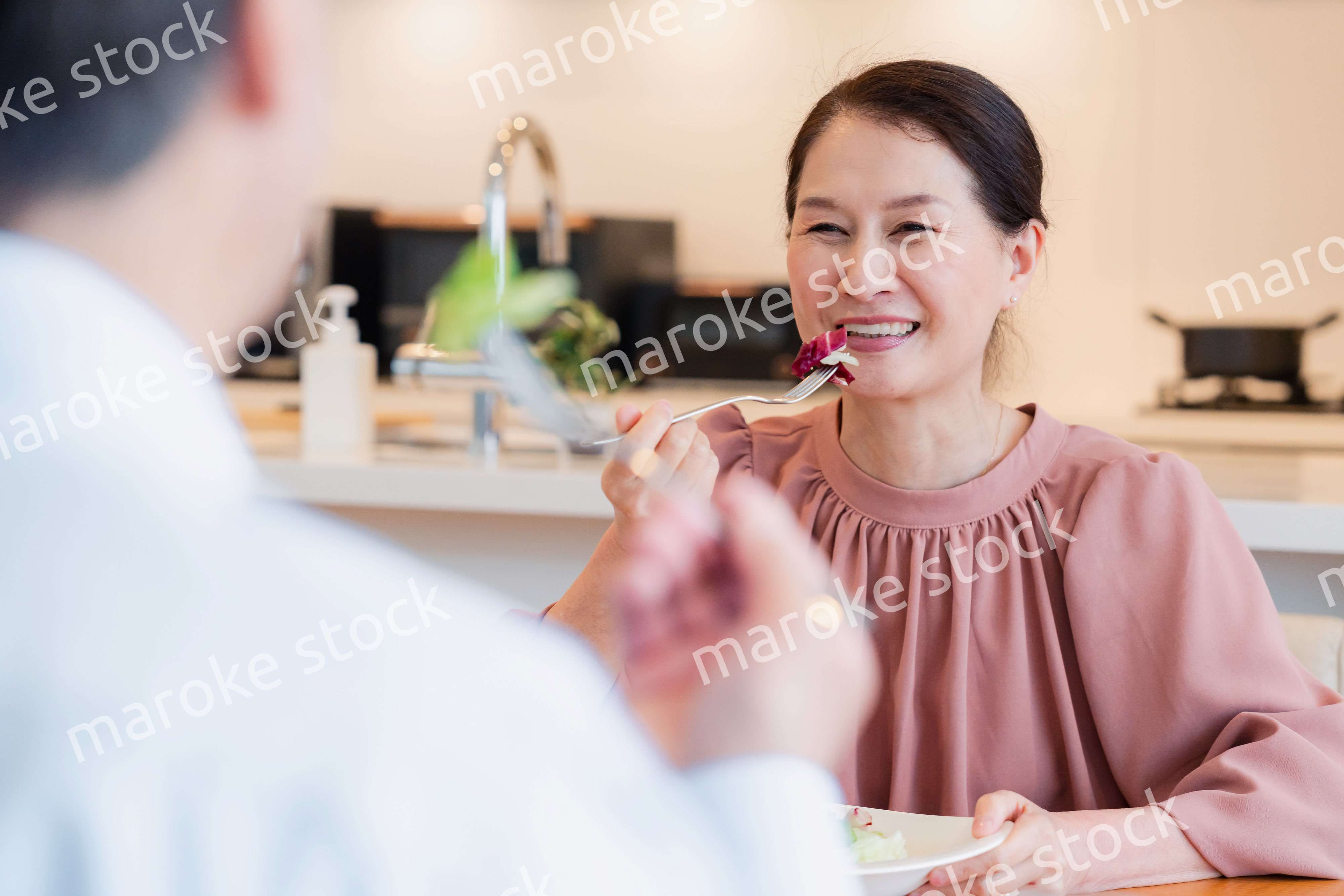 夫婦で楽しくご飯を食べる高齢女性