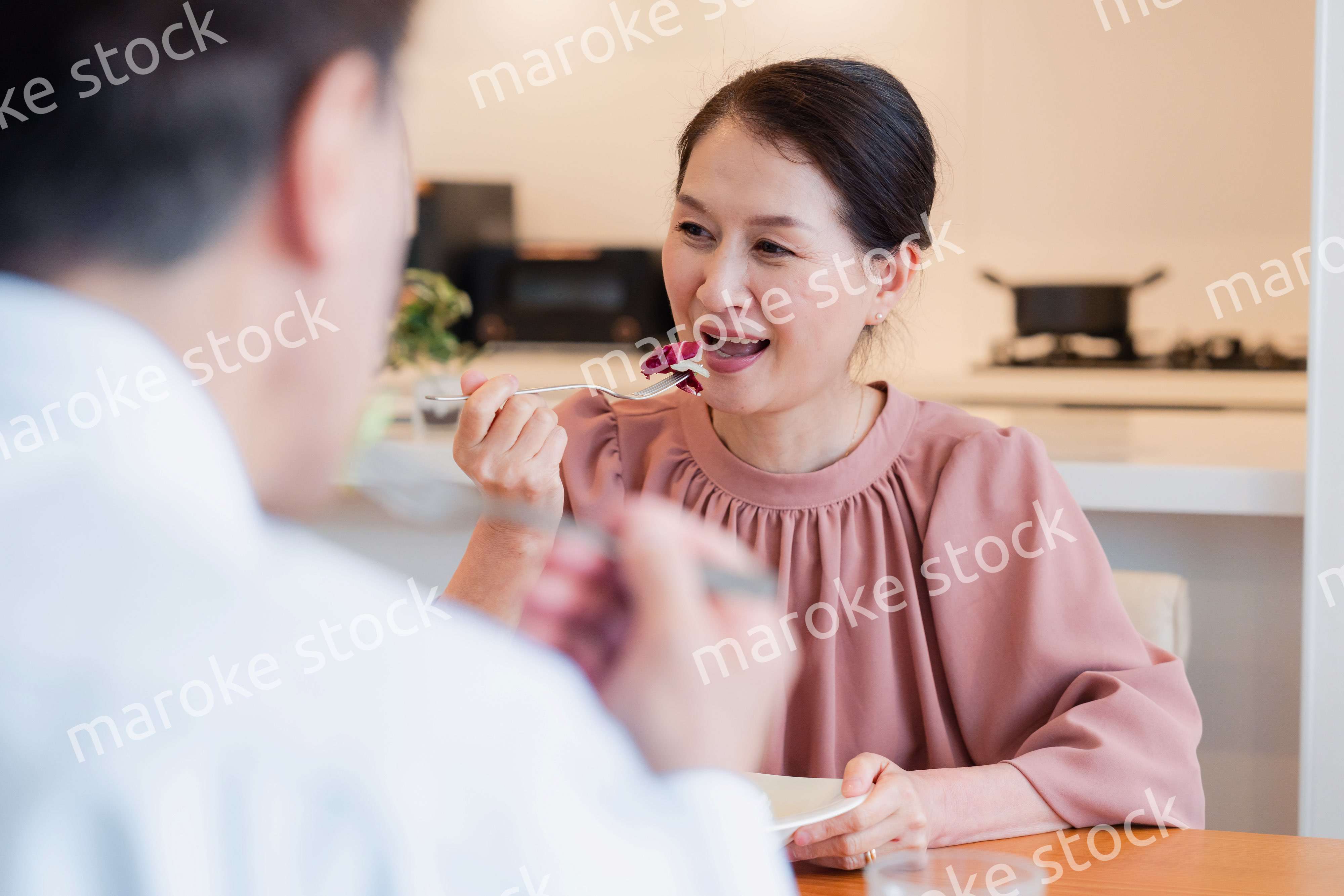 夫婦で楽しくご飯を食べる高齢女性
