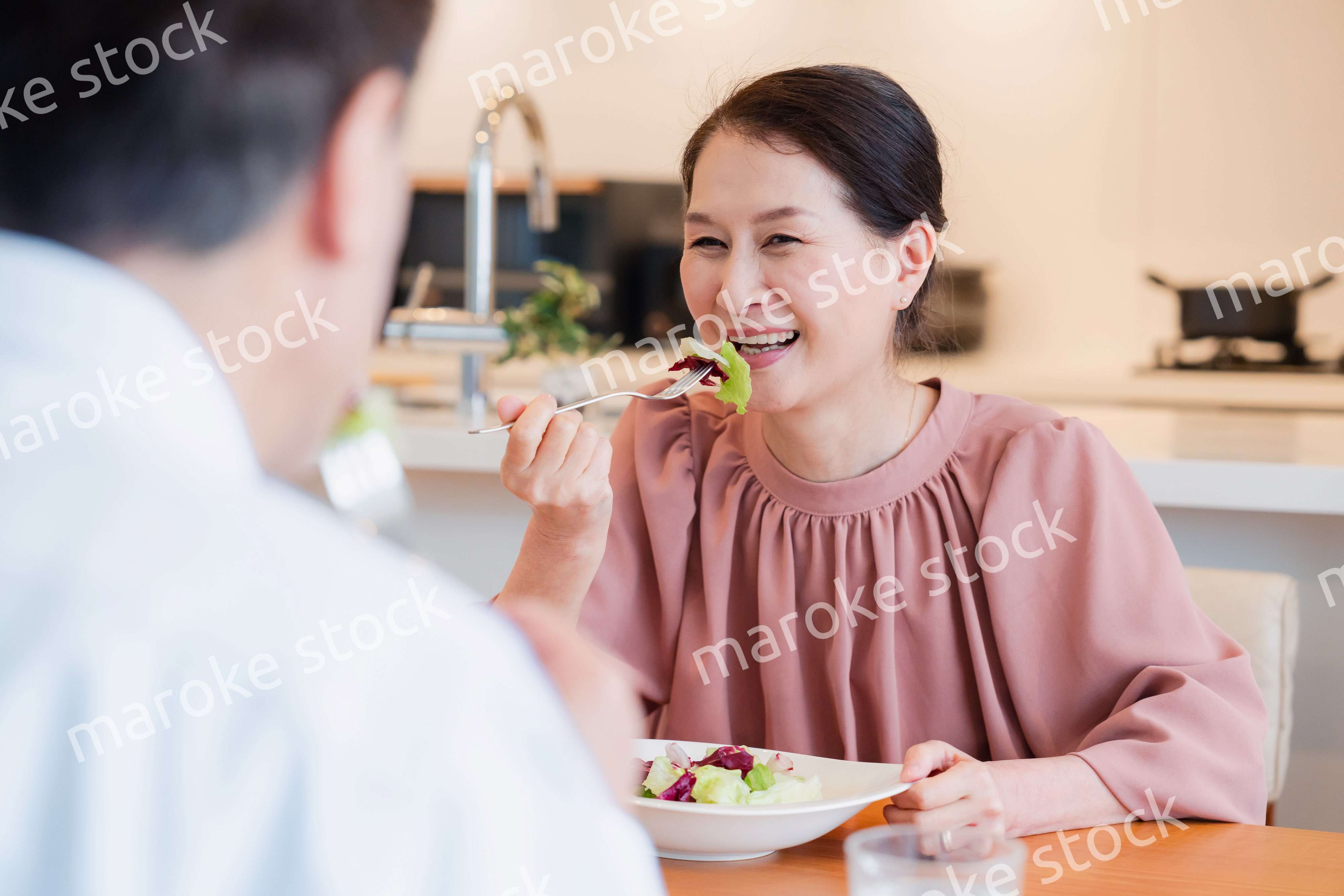 夫婦で楽しくご飯を食べる高齢女性