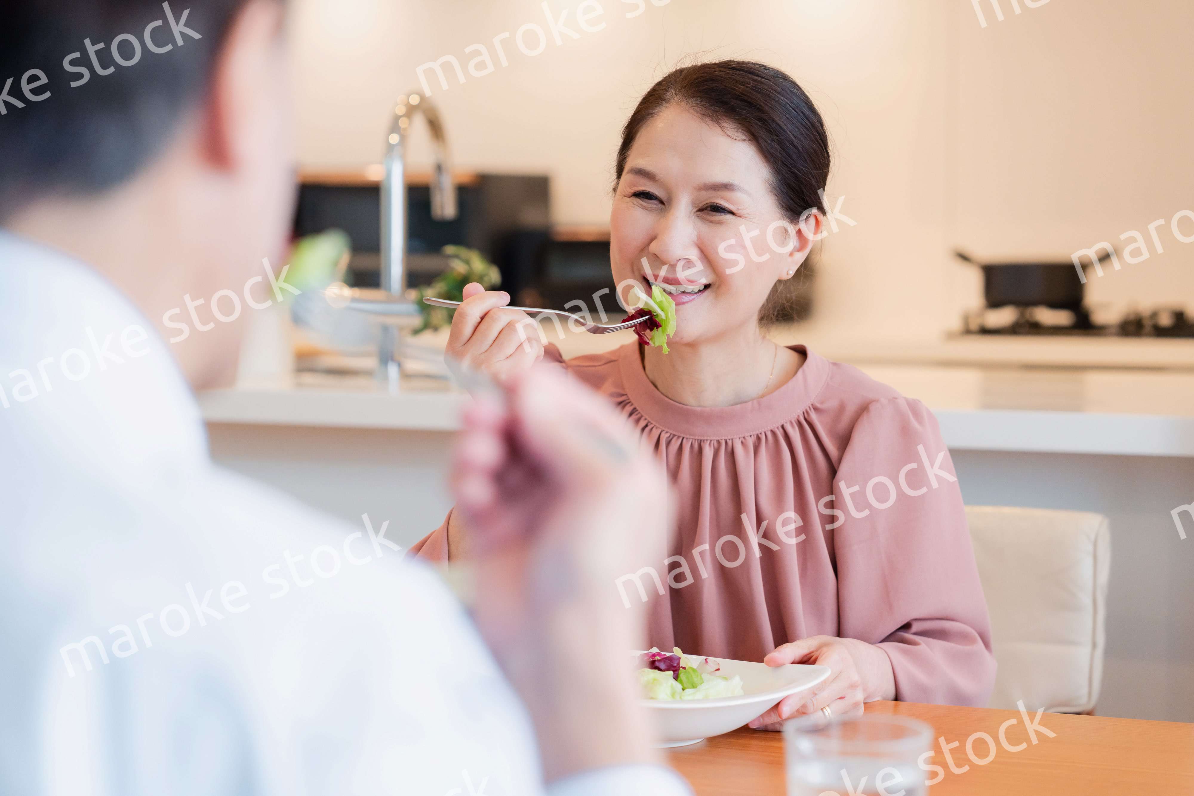 夫婦で楽しくご飯を食べる高齢女性
