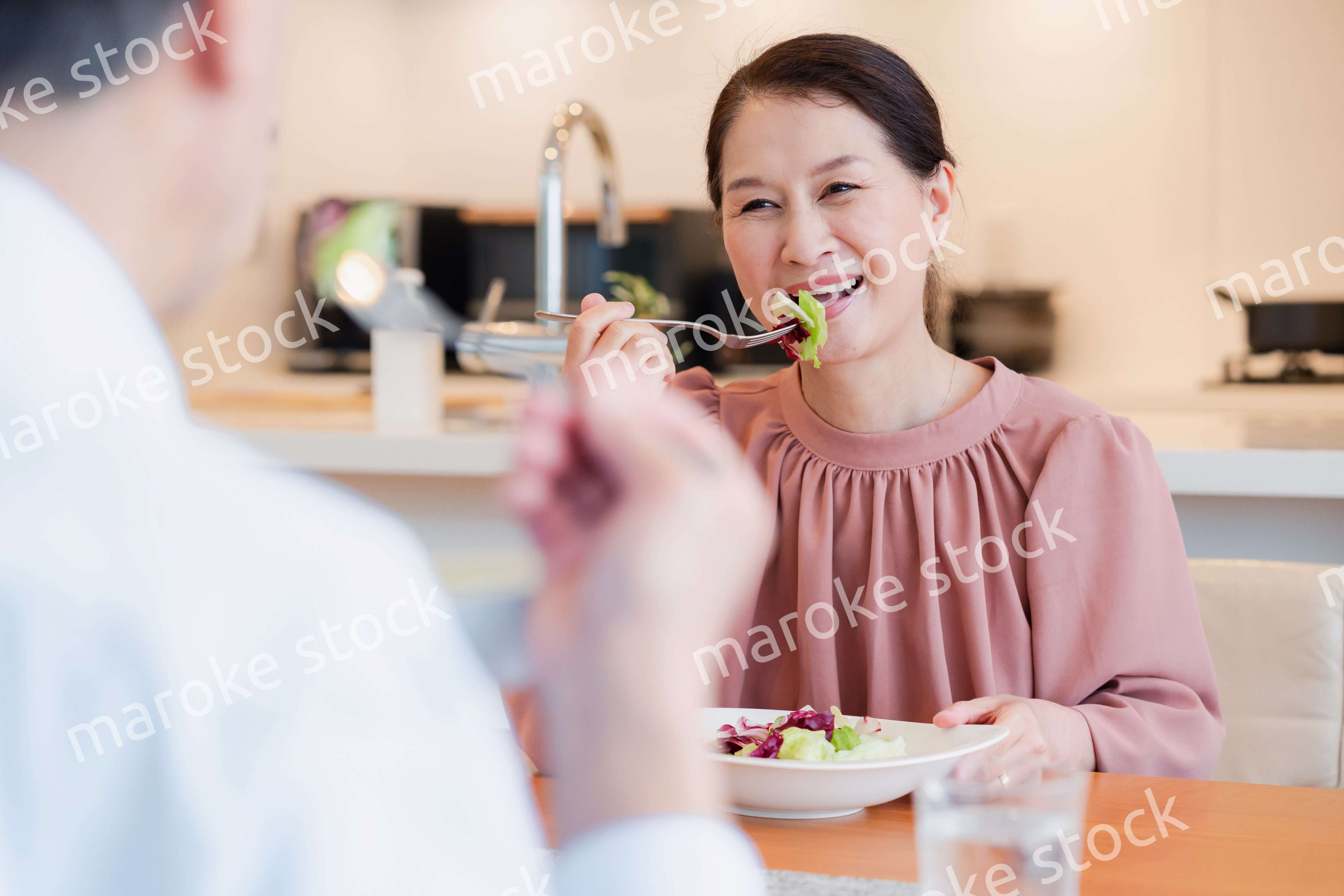 夫婦で楽しくご飯を食べる高齢女性