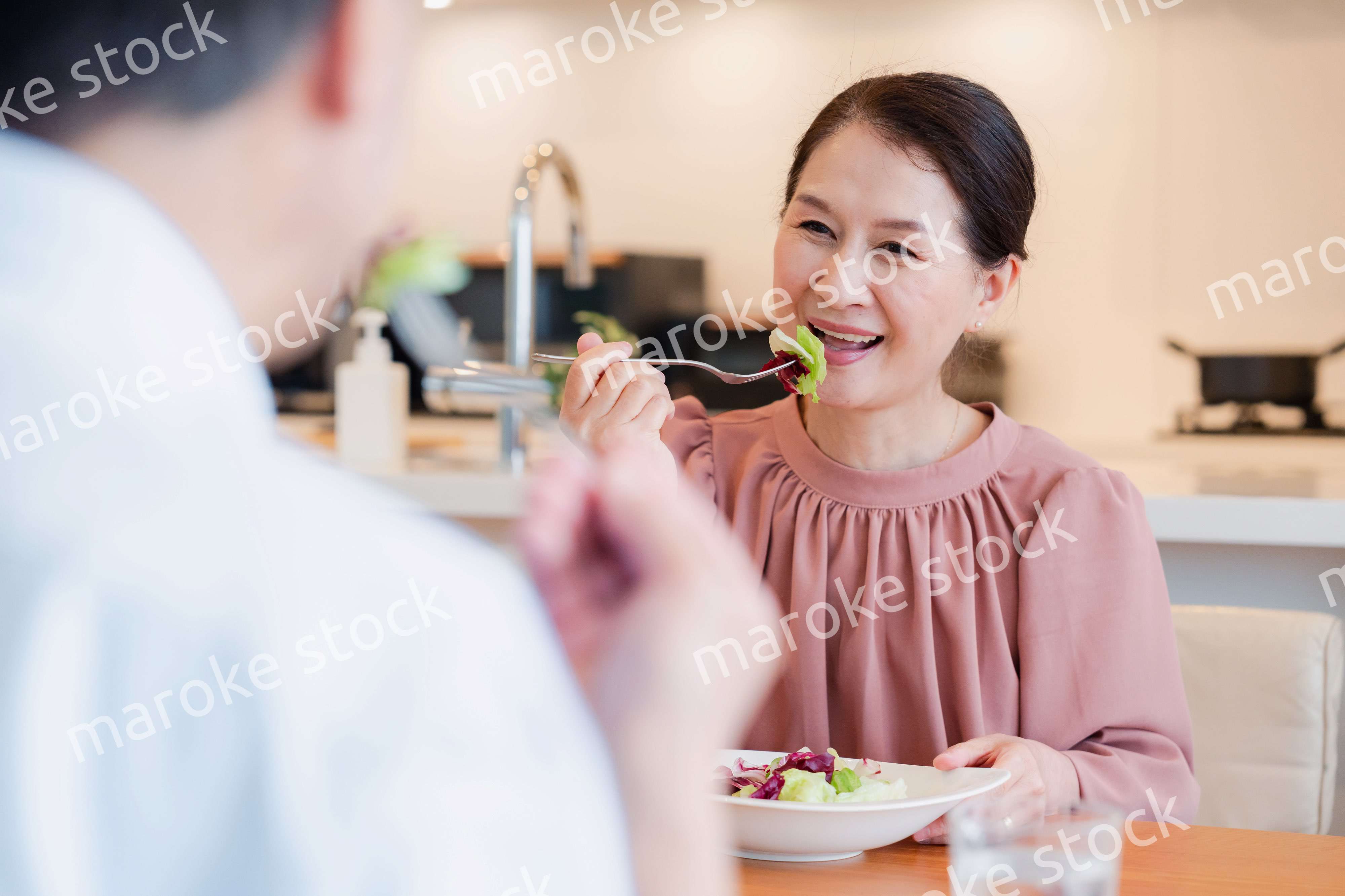 夫婦で楽しくご飯を食べる高齢女性