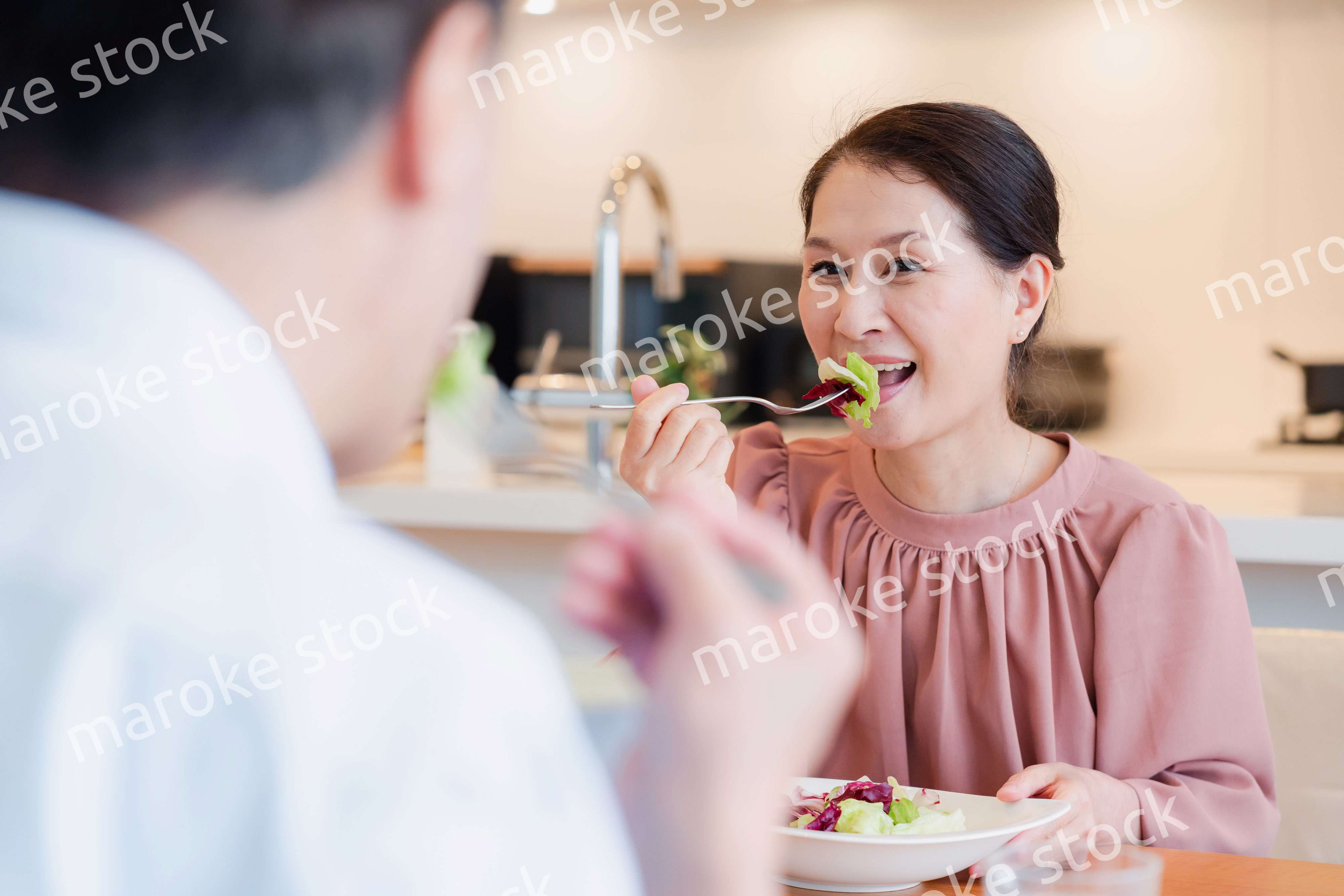夫婦で楽しくご飯を食べる高齢女性
