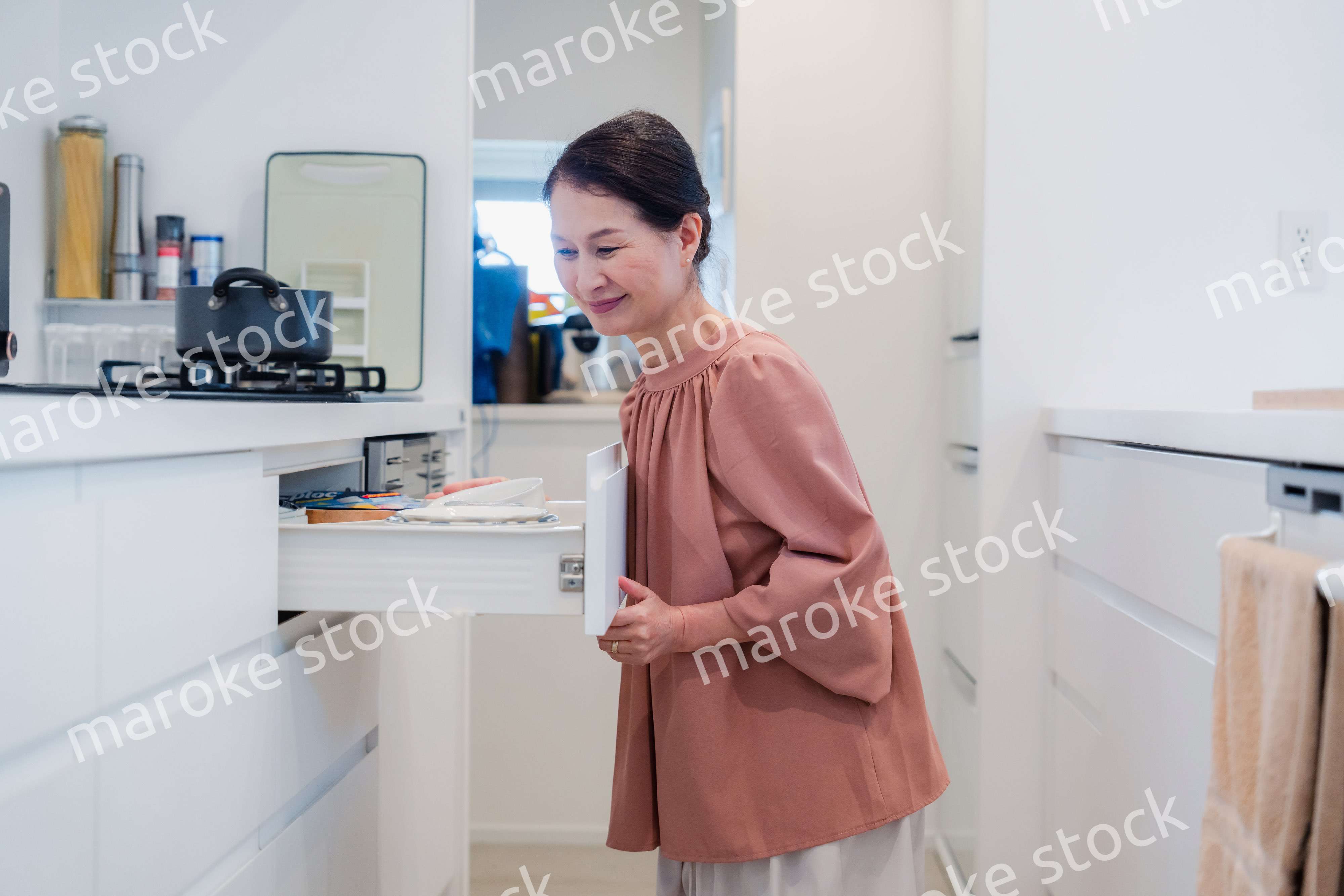 キッチンの収納を工夫するシニアの女性