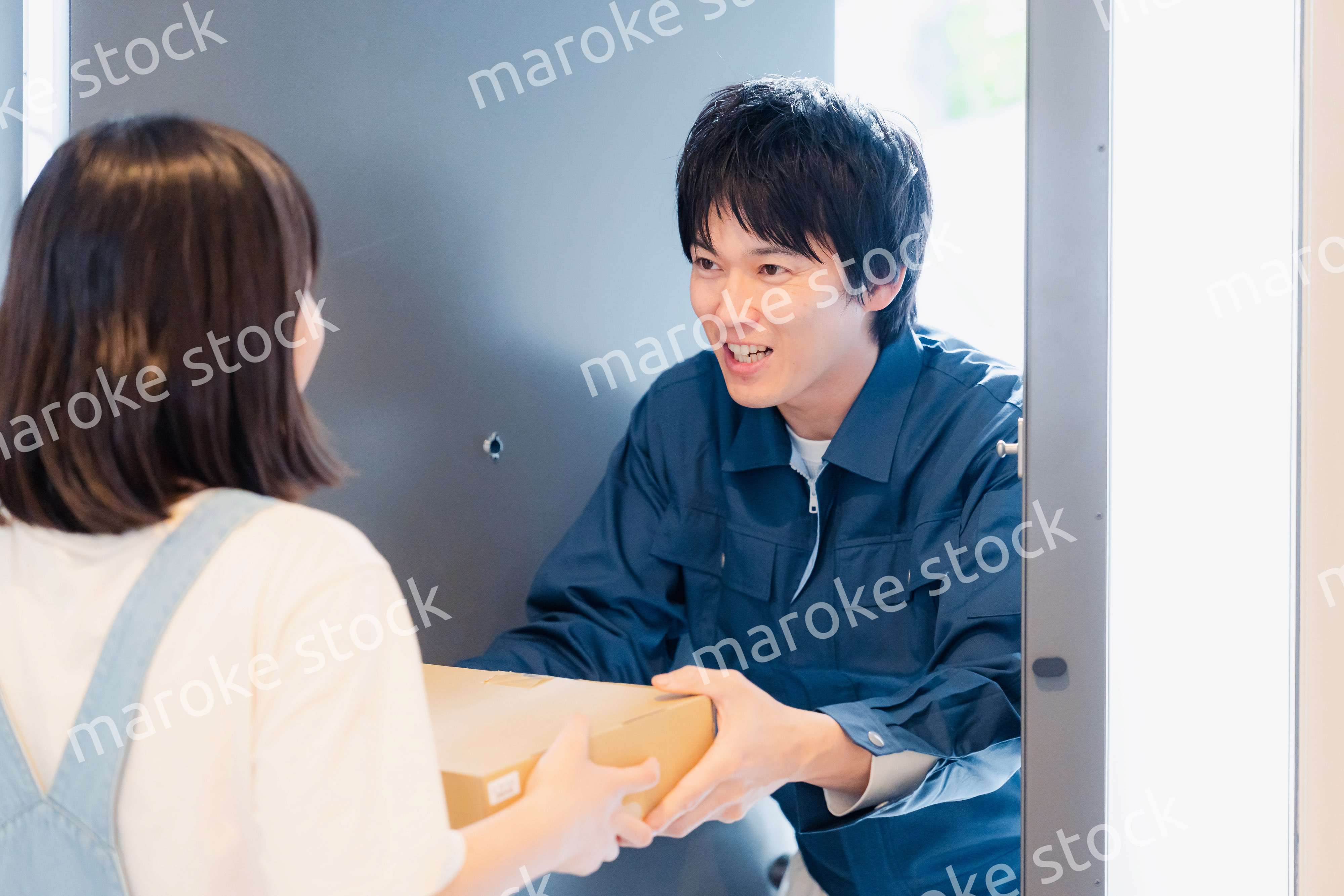 笑顔で宅配便の配達をする若い男性