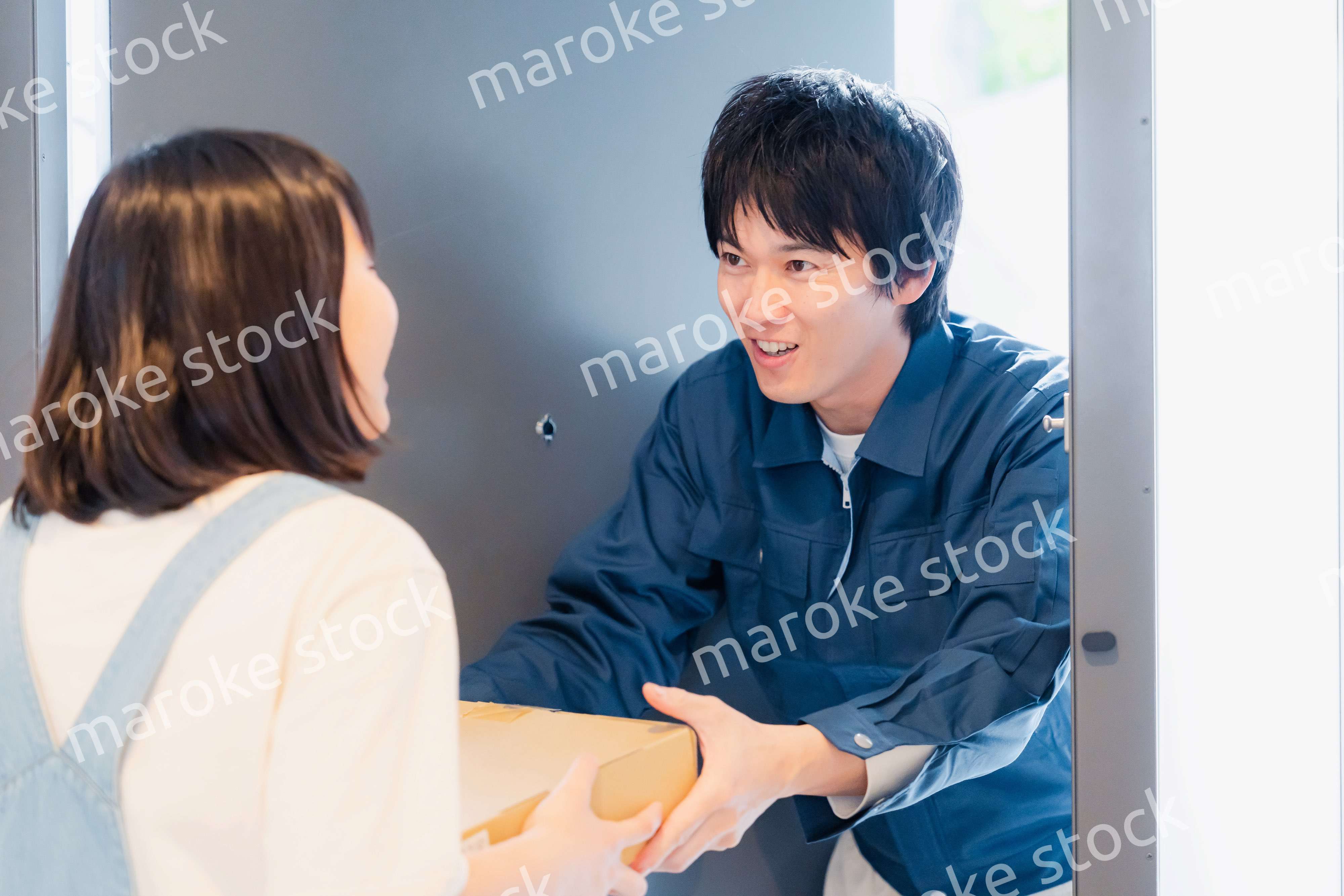 笑顔で宅配便の配達をする若い男性