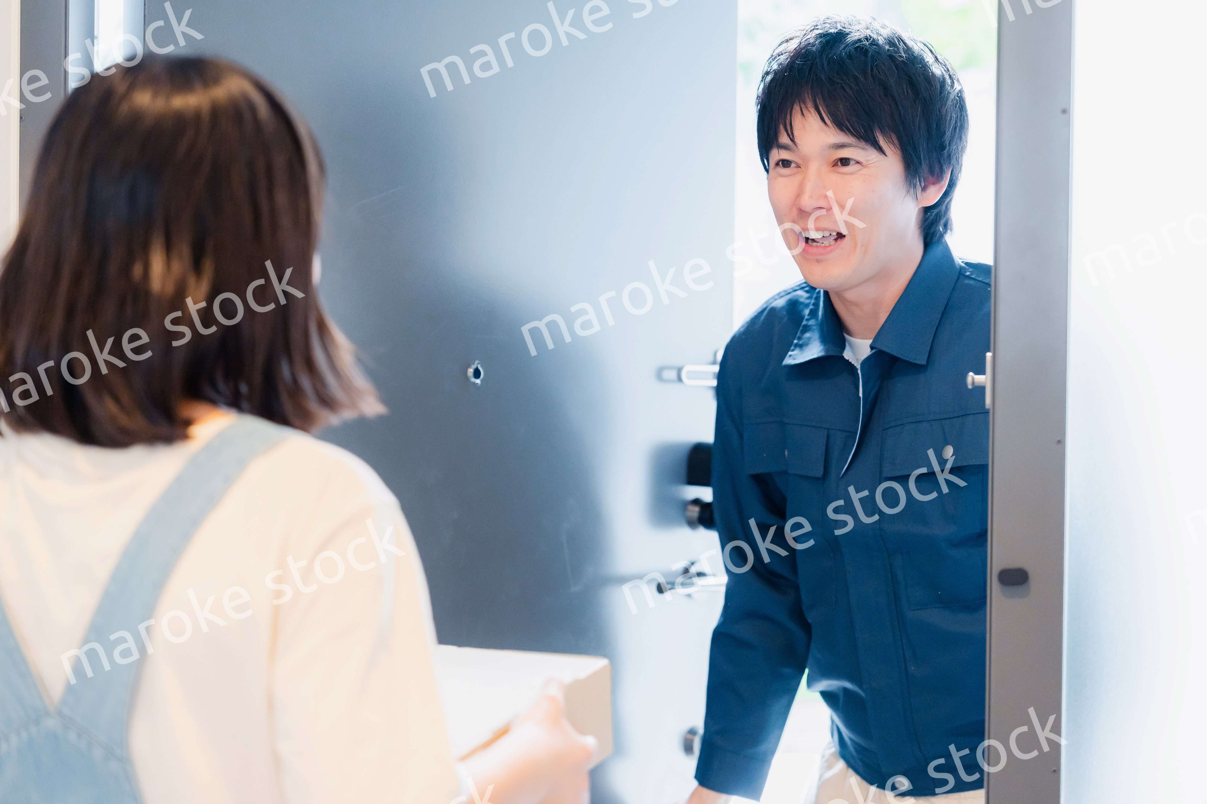 笑顔で宅配便の配達をする若い男性