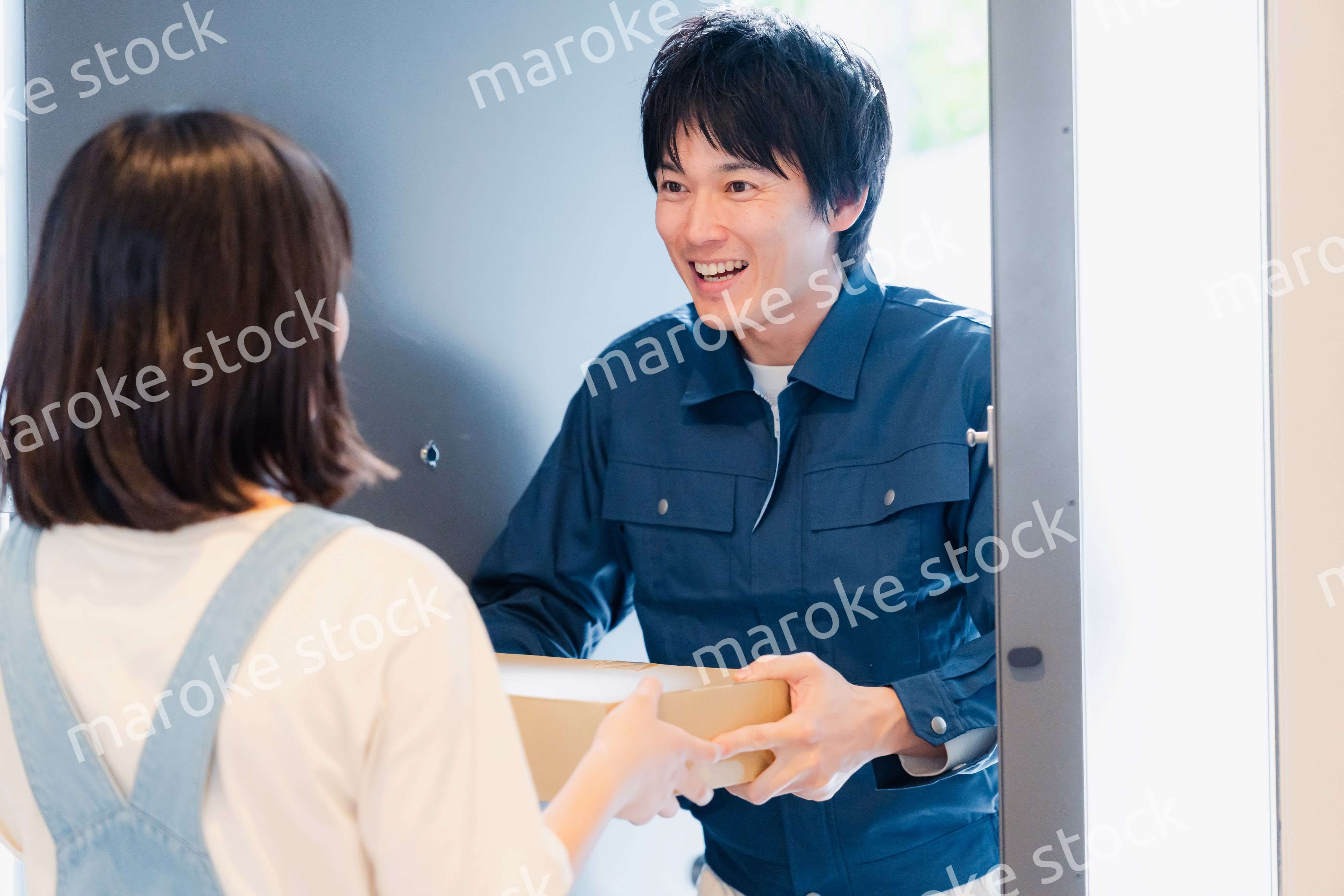 笑顔で宅配便の配達をする若い男性