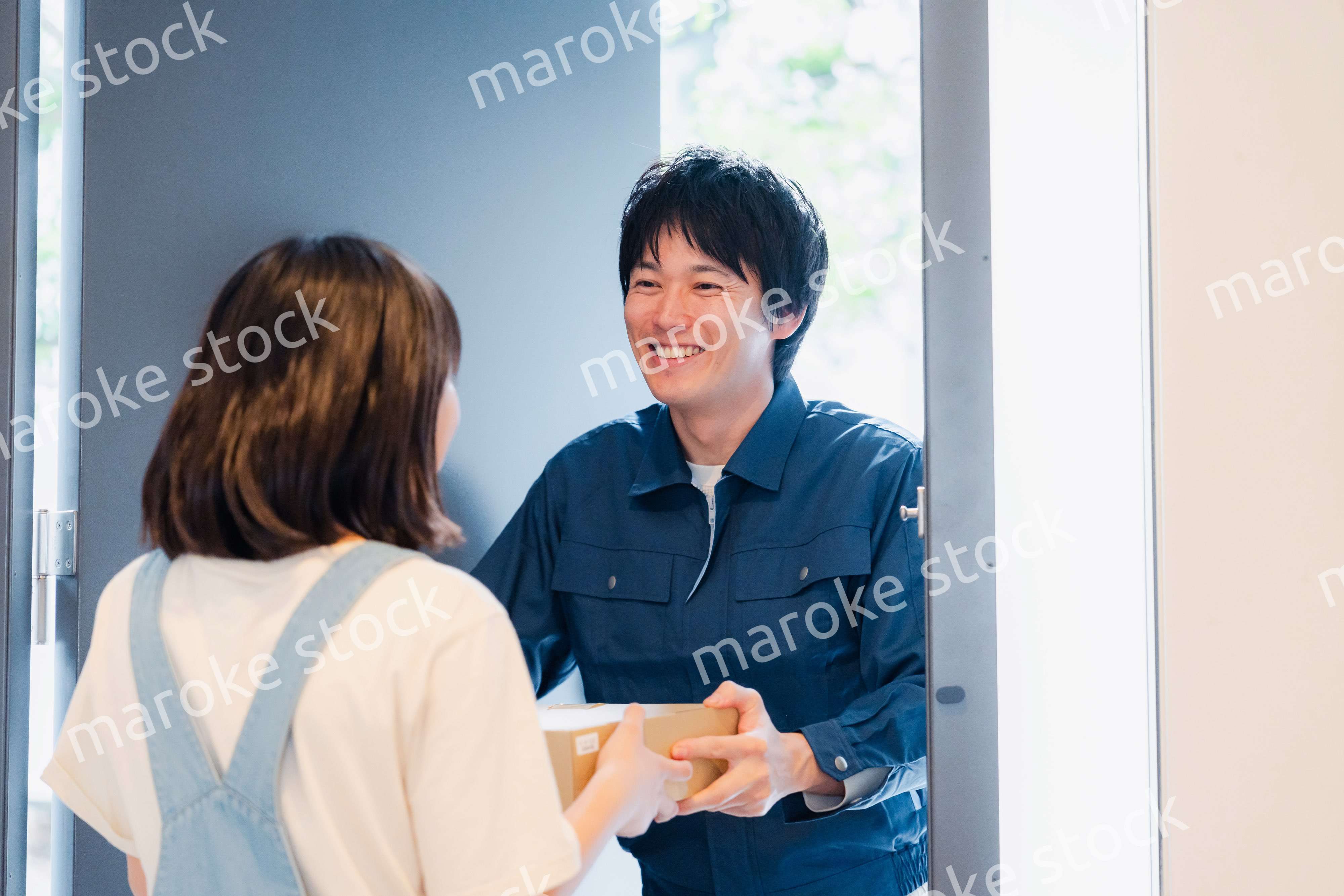 笑顔で宅配便の配達をする若い男性