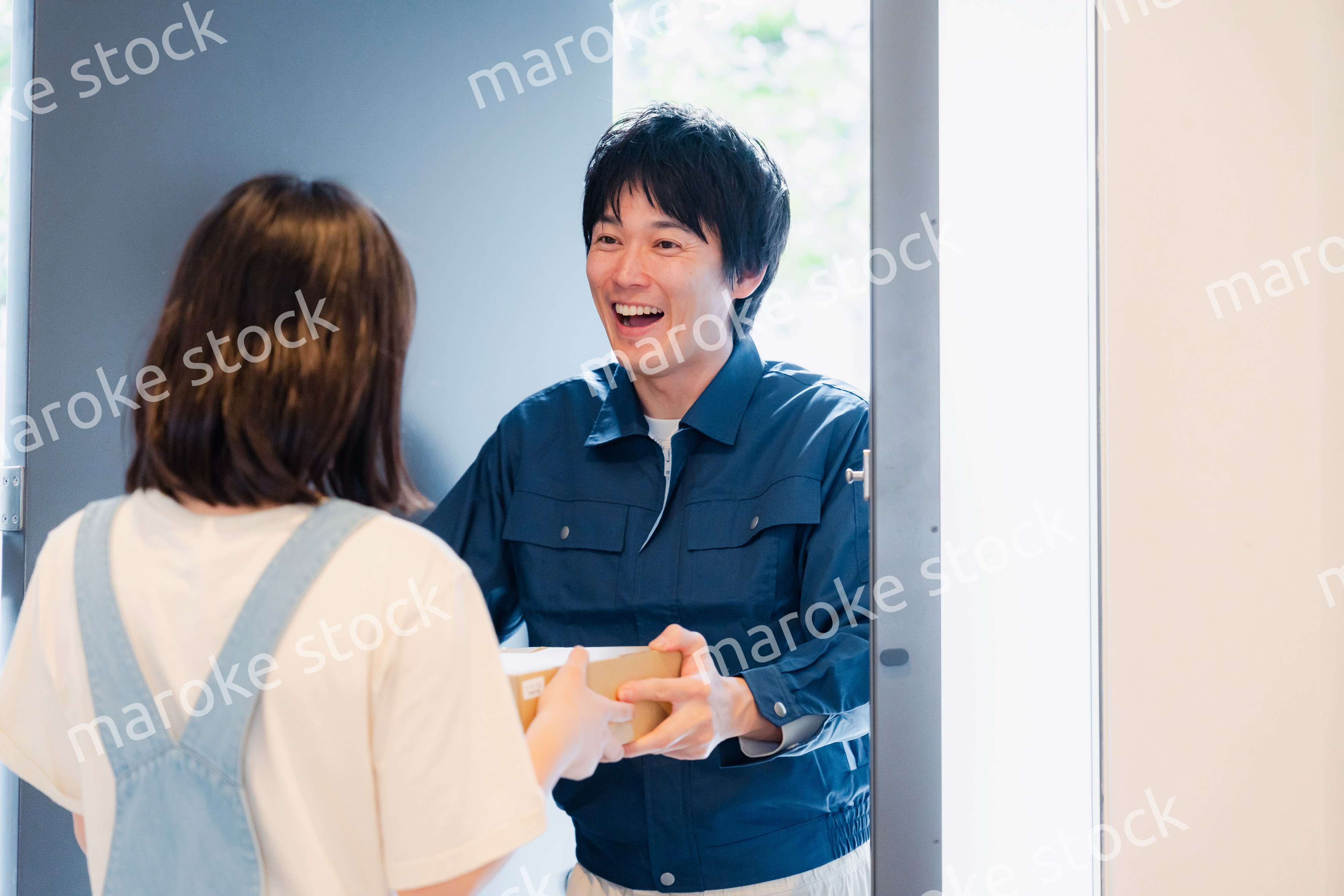 笑顔で宅配便の配達をする若い男性