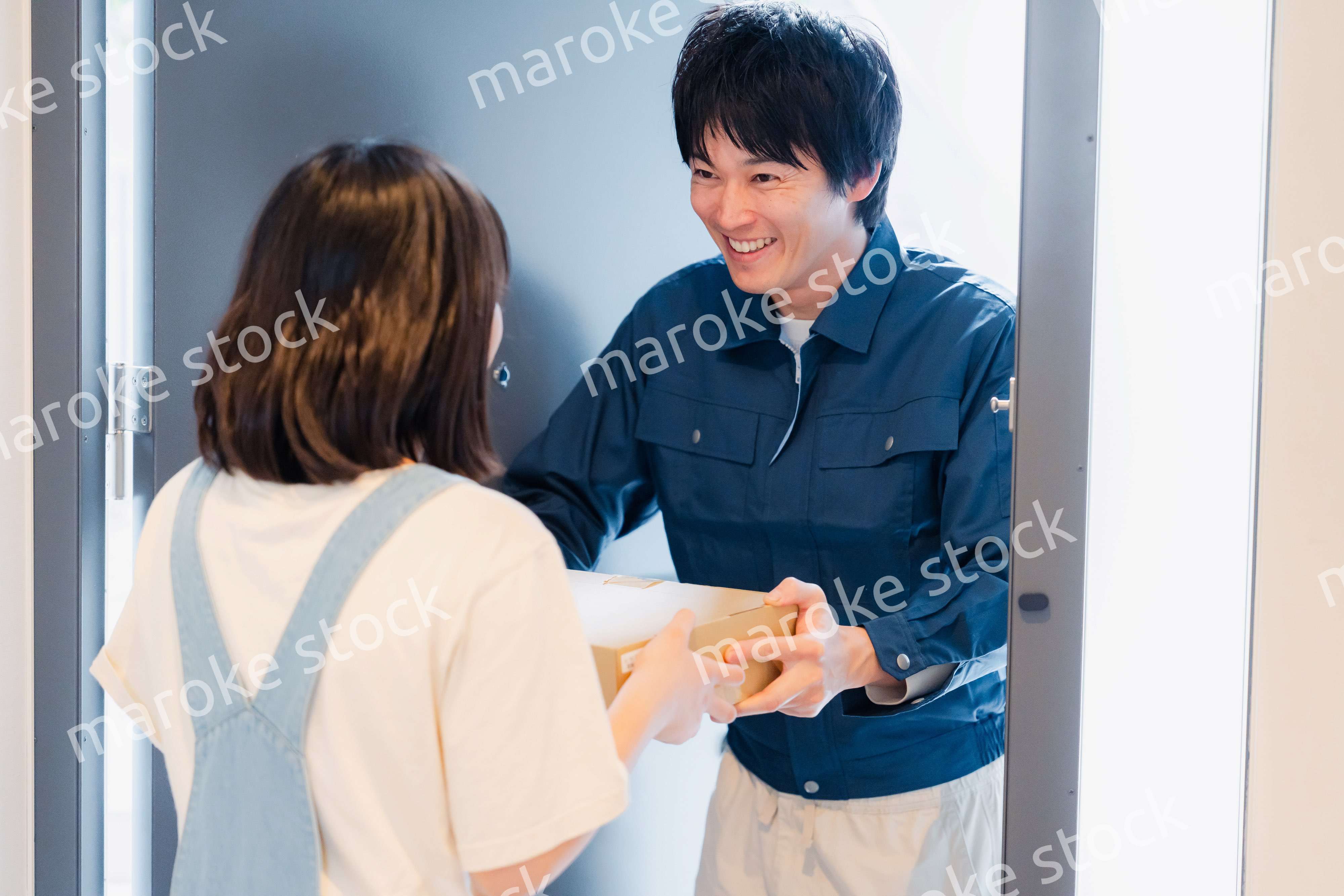 笑顔で宅配便の配達をする若い男性