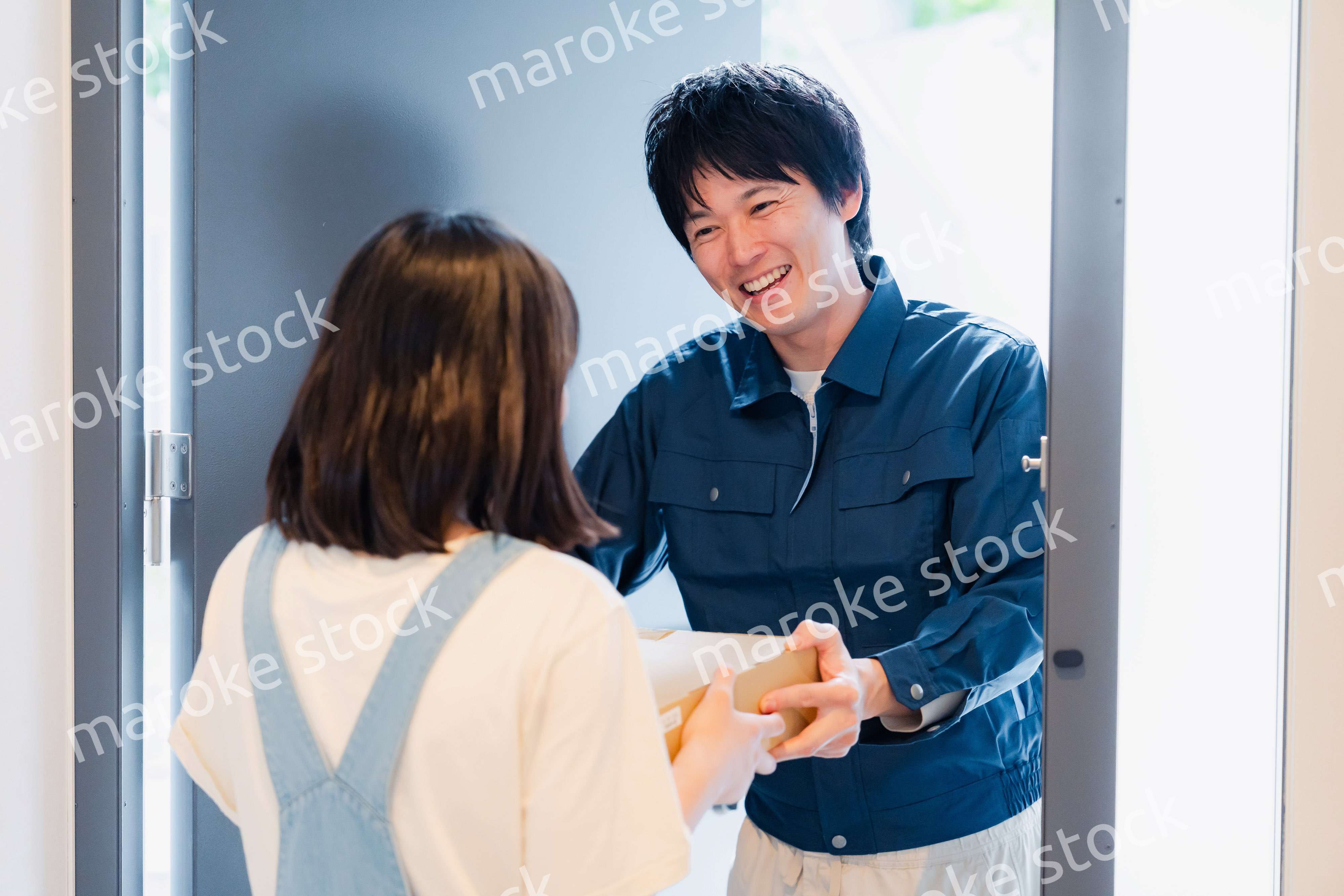 笑顔で宅配便の配達をする若い男性