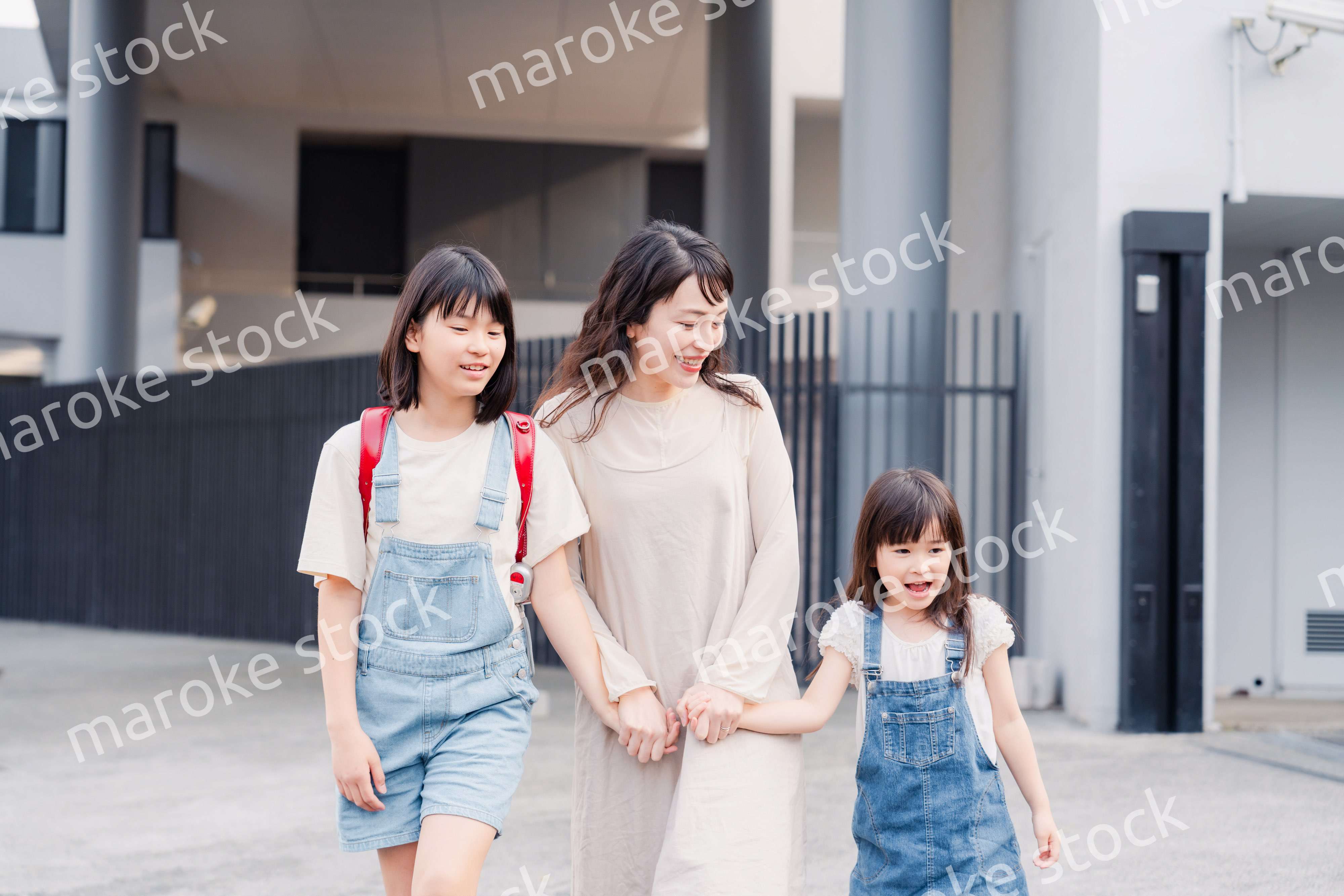 お母さんと手を繋いで学校に行く2人の女の子