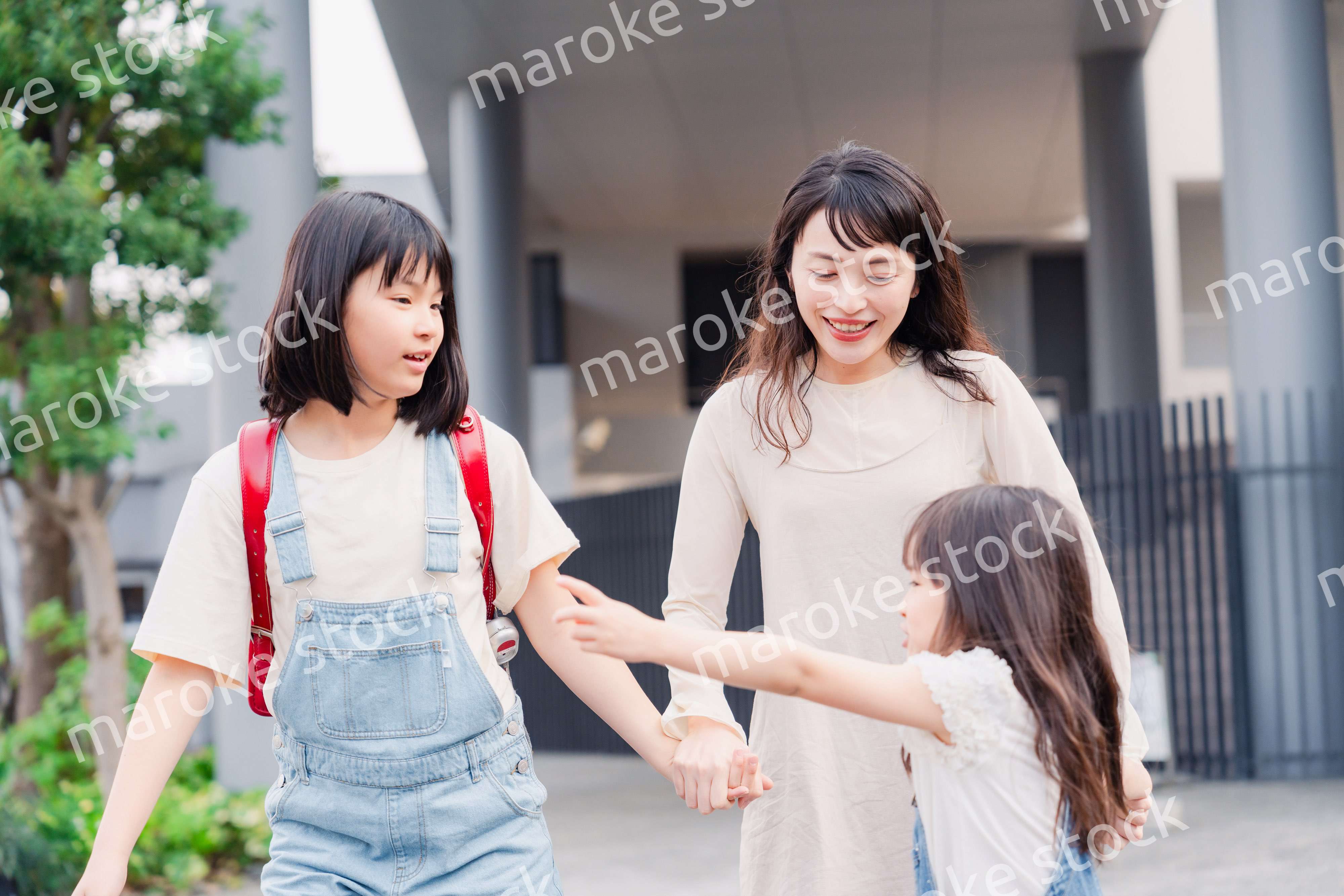 お母さんと手を繋いで学校に行く2人の女の子