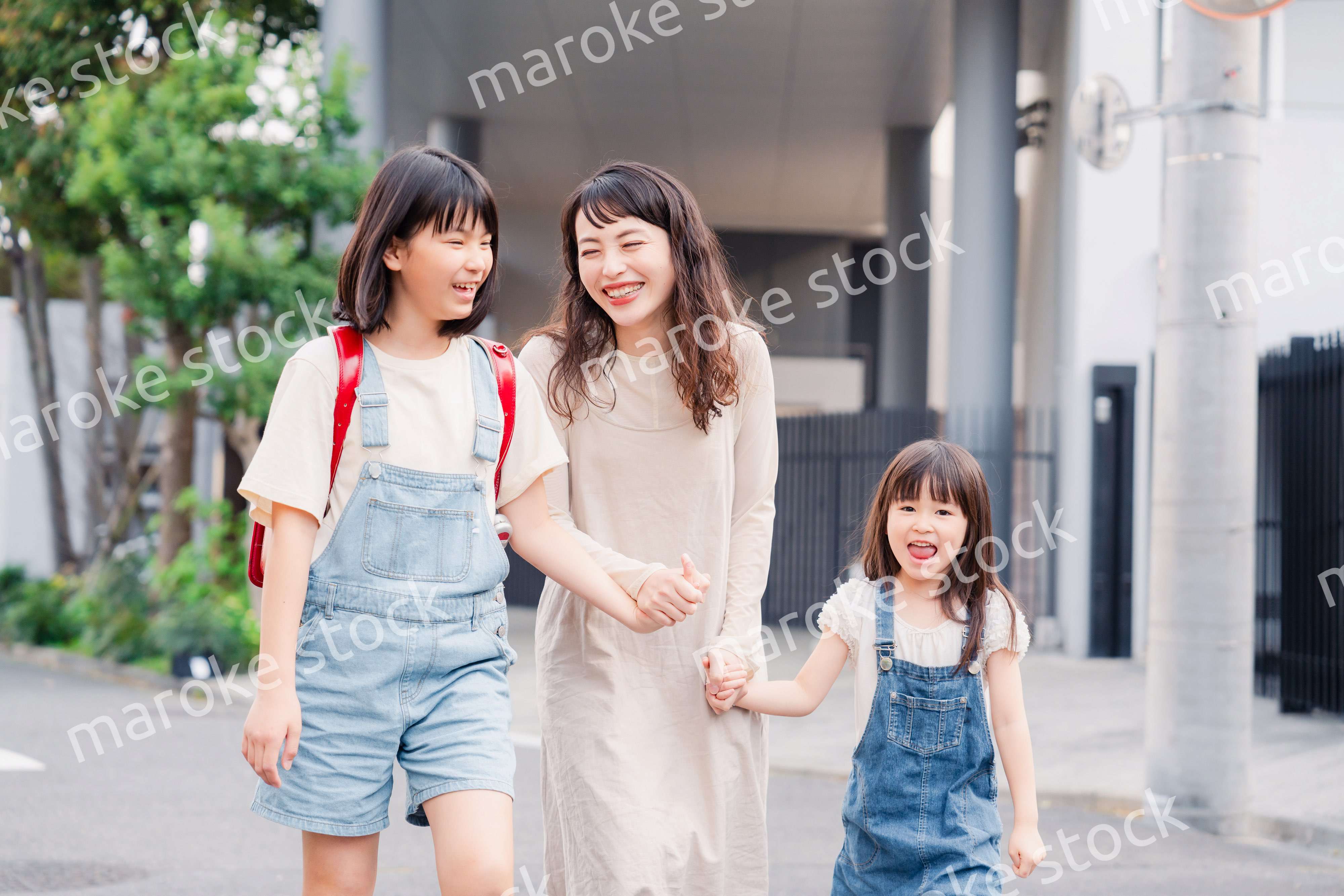 お母さんと手を繋いで学校に行く2人の女の子