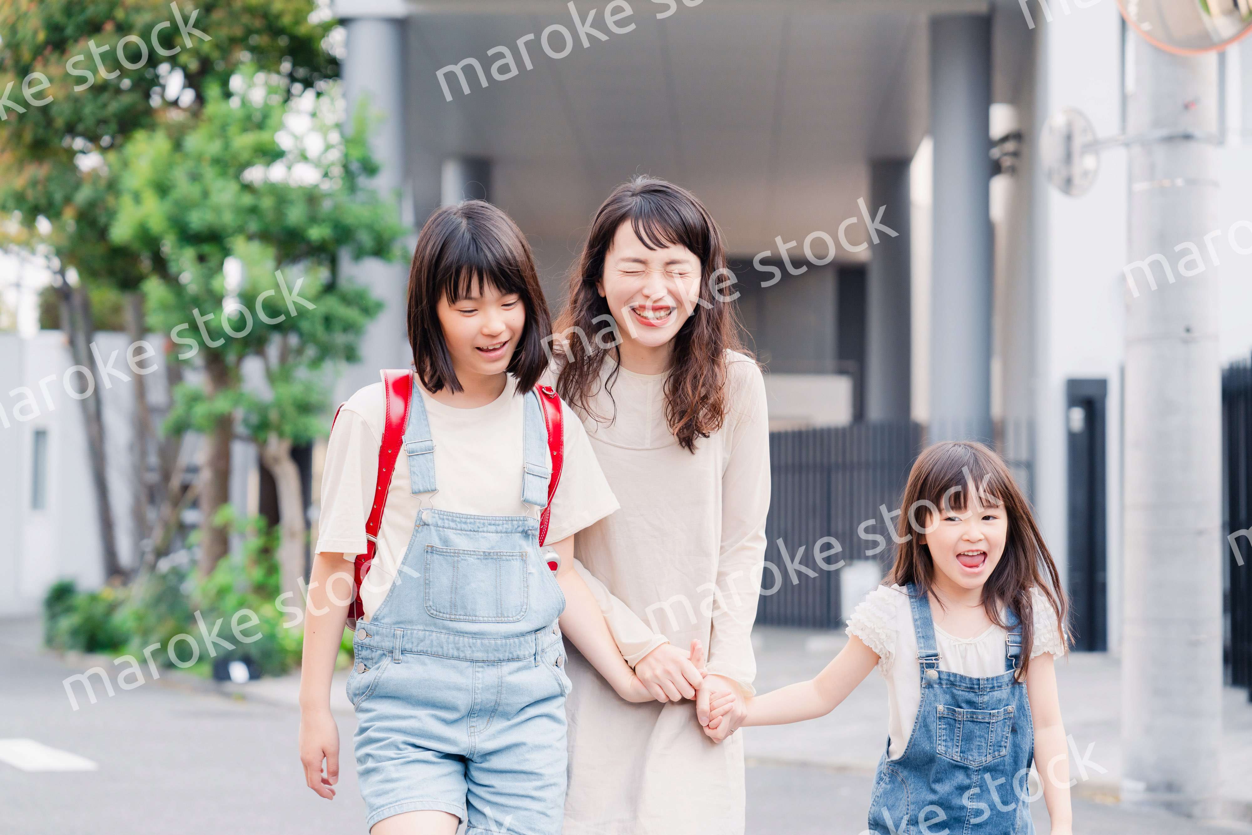 お母さんと手を繋いで学校に行く2人の女の子