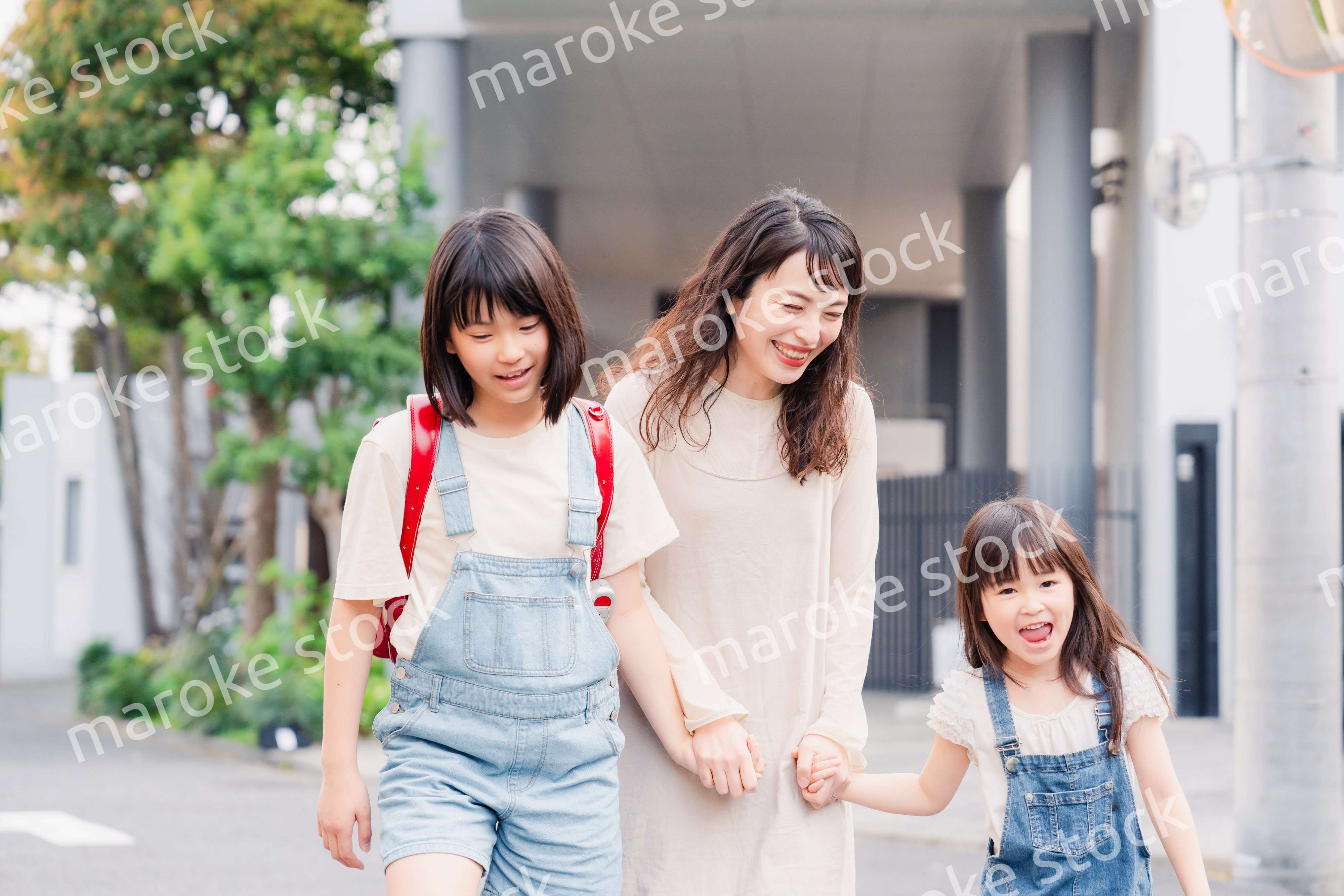お母さんと手を繋いで学校に行く2人の女の子