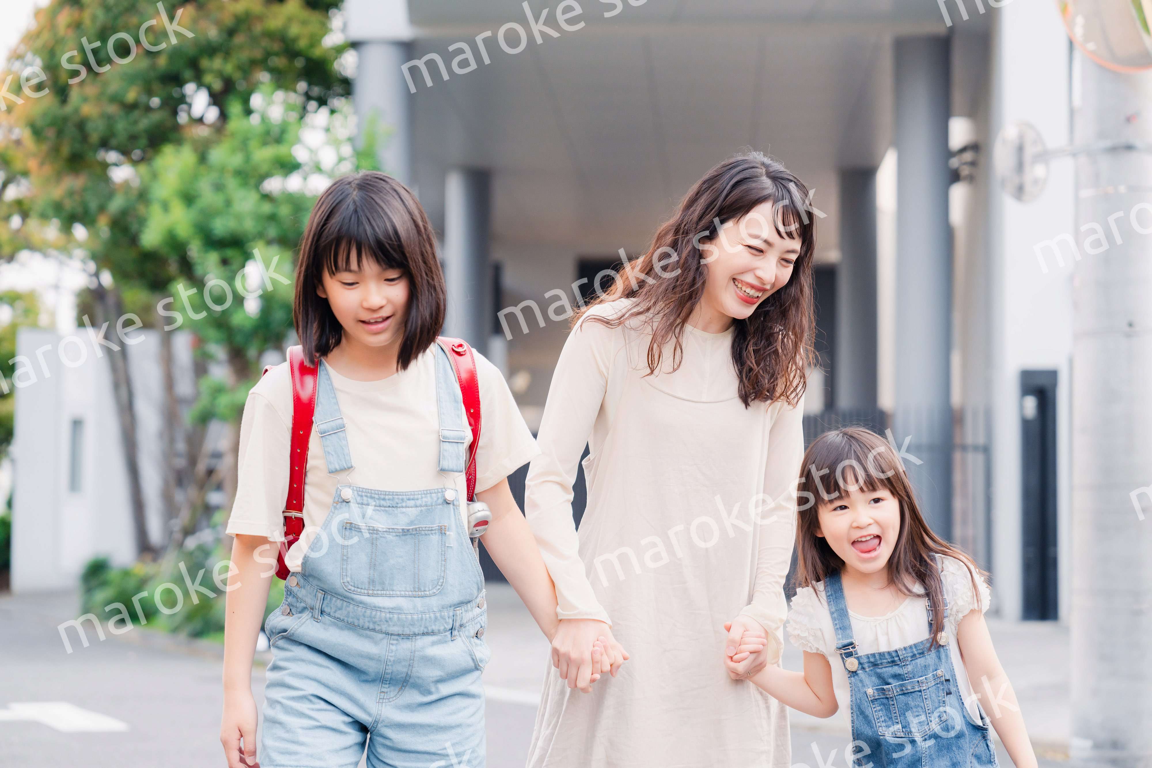 お母さんと手を繋いで学校に行く2人の女の子