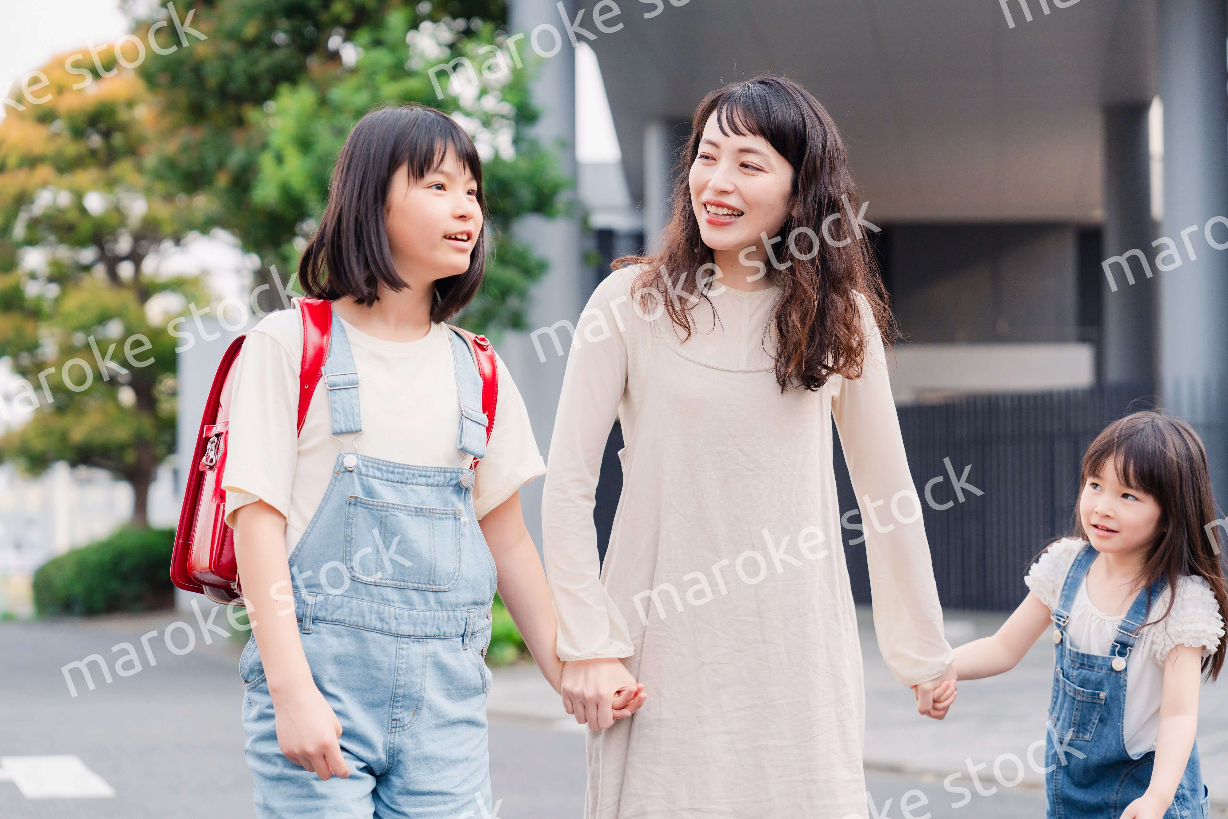 お母さんと手を繋いで学校に行く2人の女の子