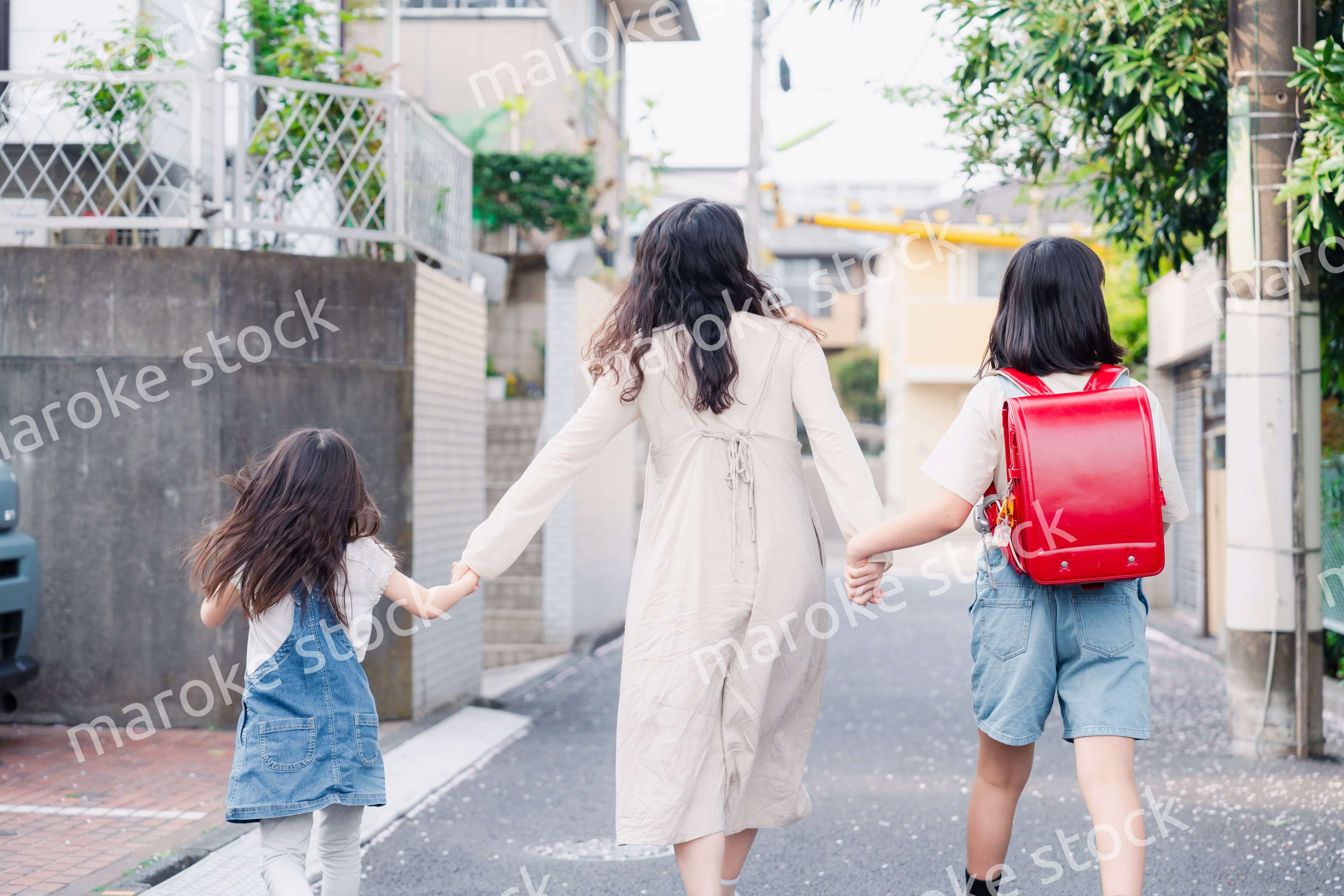 お母さんと手を繋いで学校に行く2人の女の子