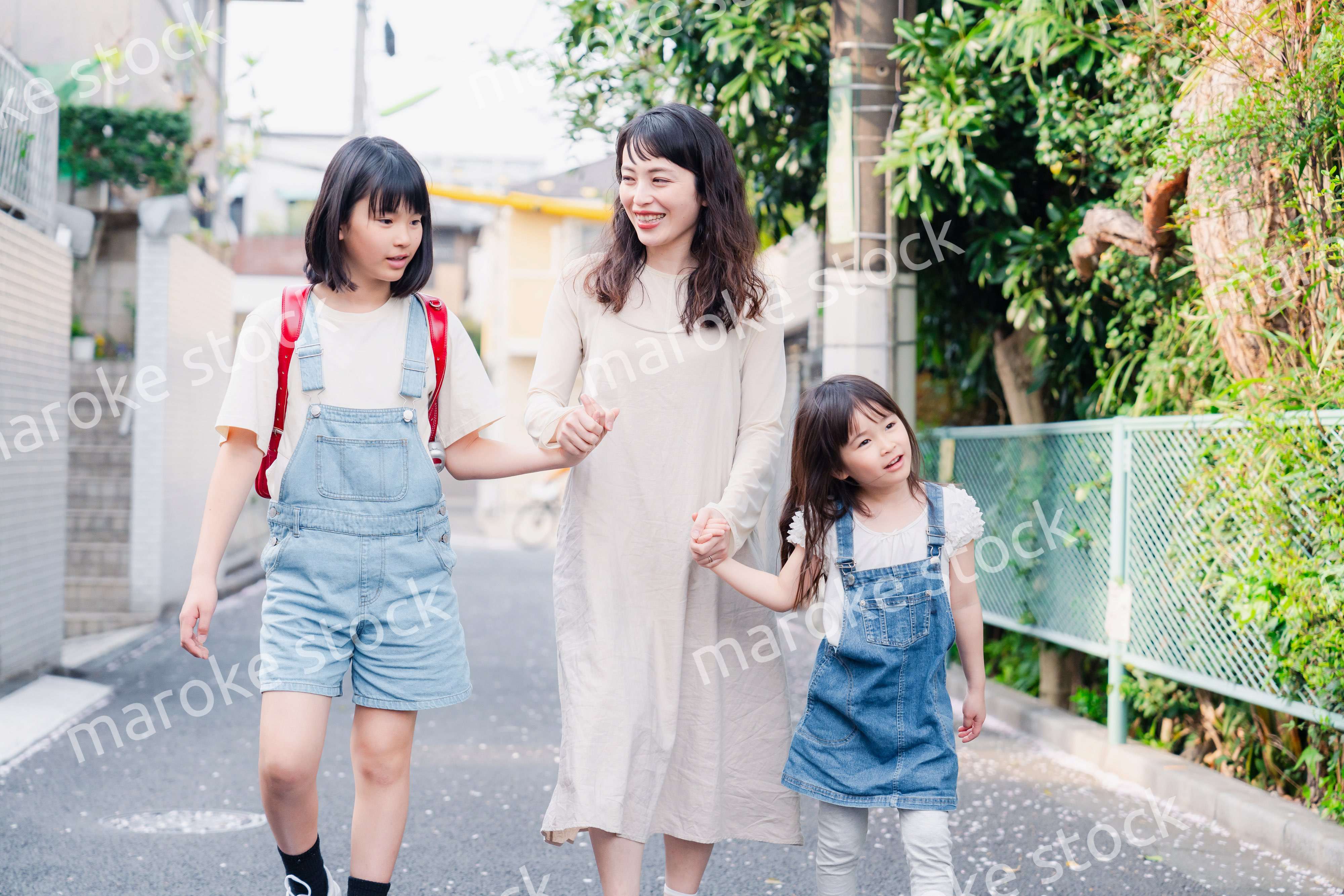 お母さんと手を繋いで学校に行く2人の女の子