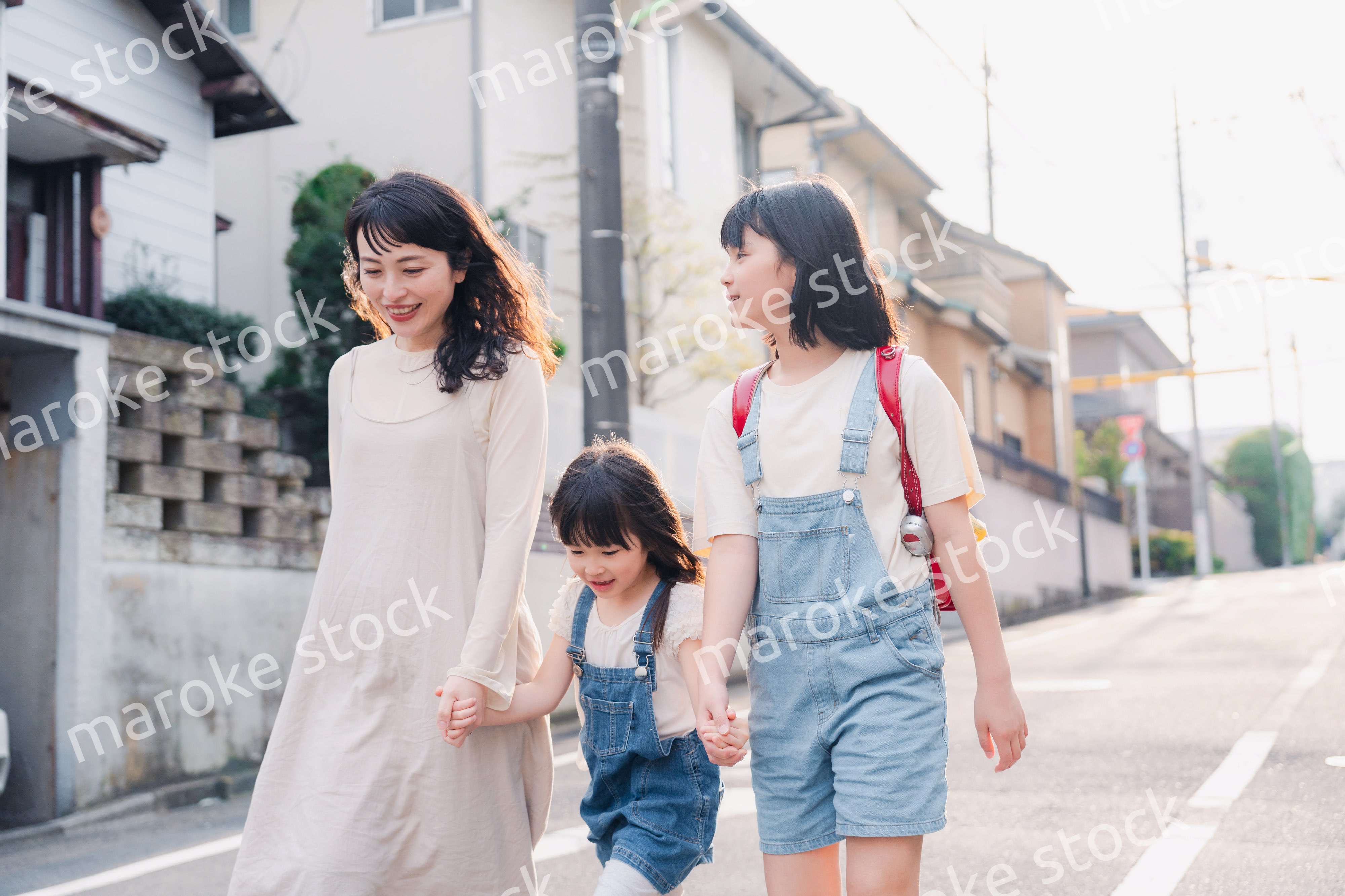 お母さんと手を繋いで学校に行く2人の女の子