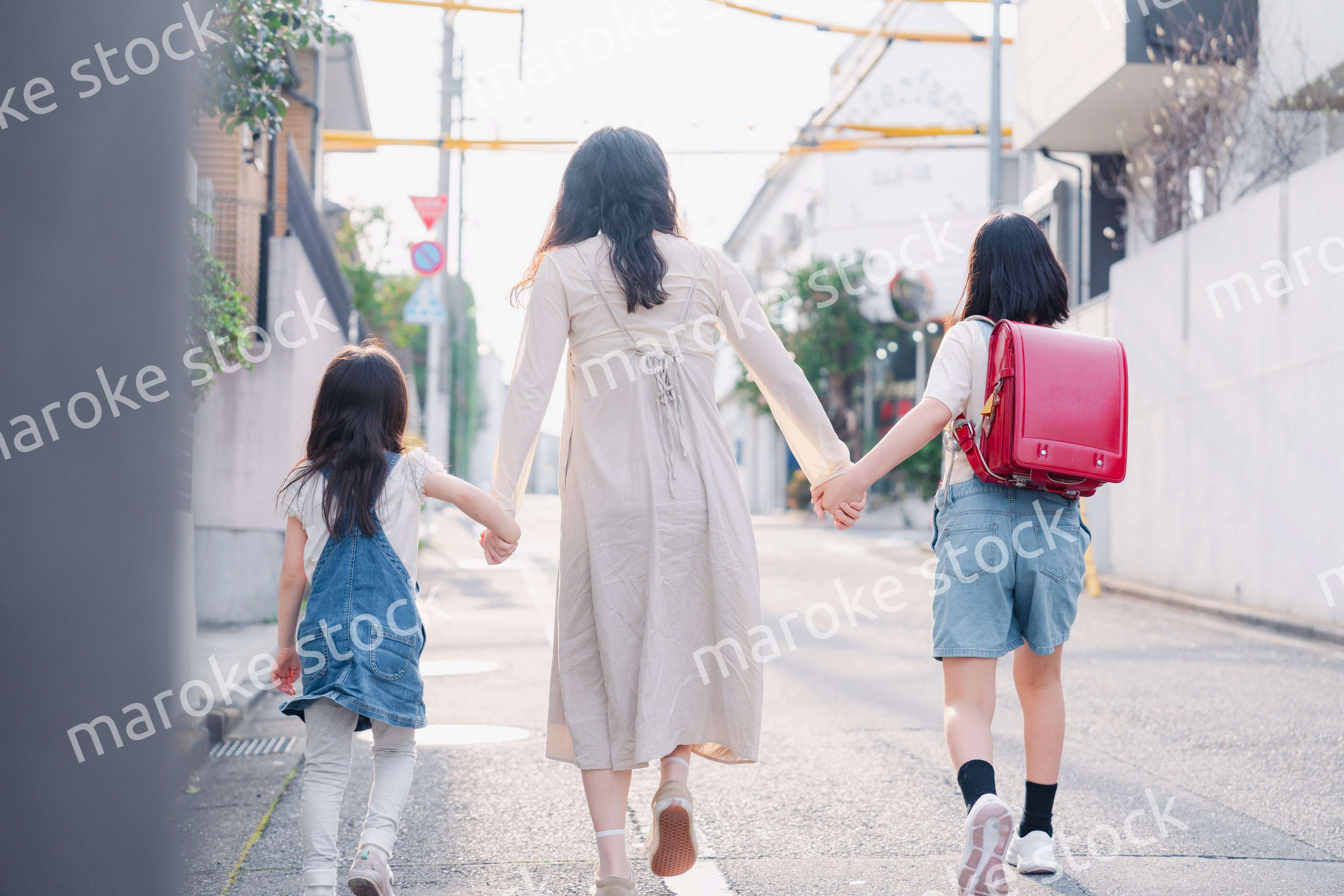 お母さんと手を繋いで学校に行く2人の女の子