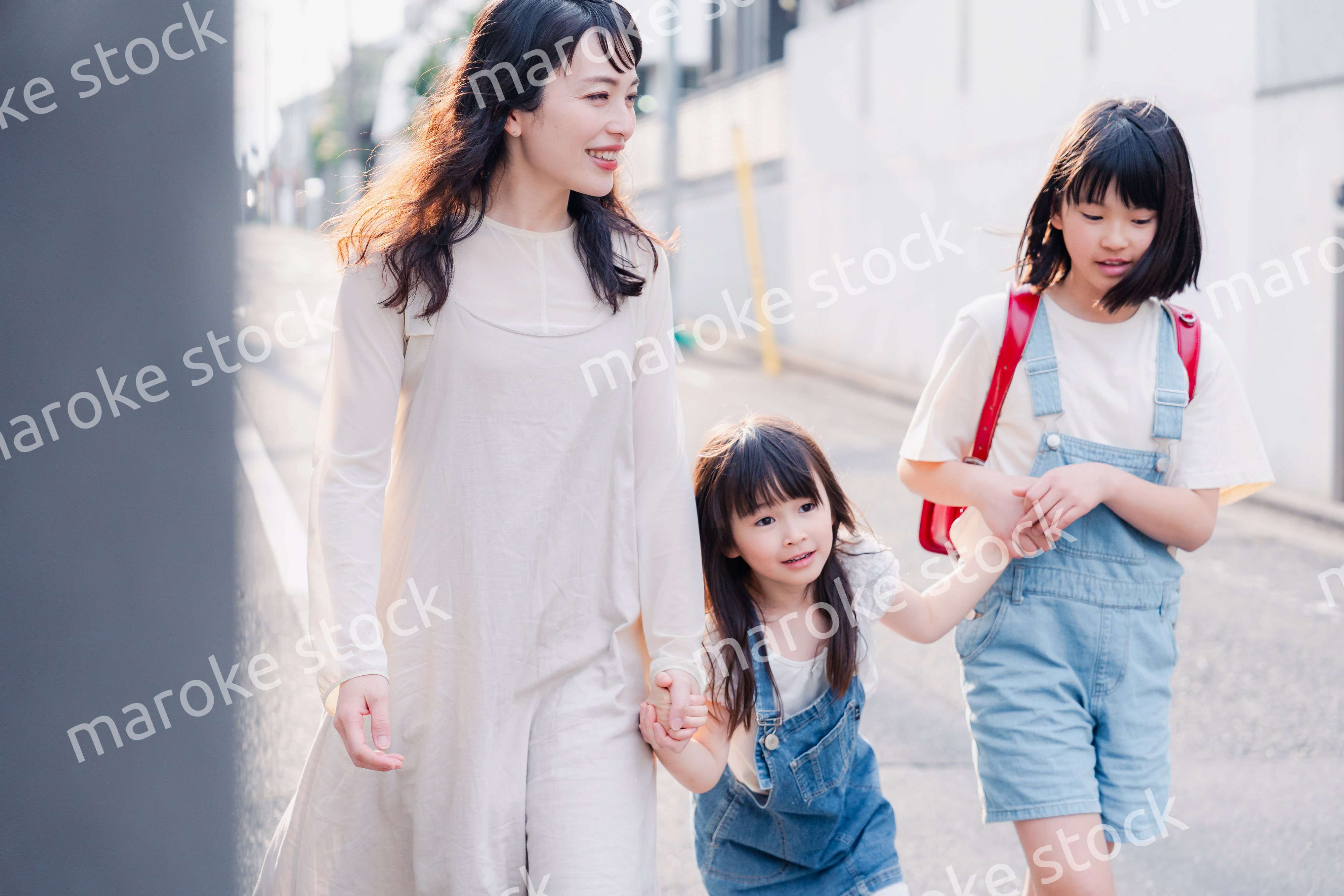 お母さんと手を繋いで学校に行く2人の女の子