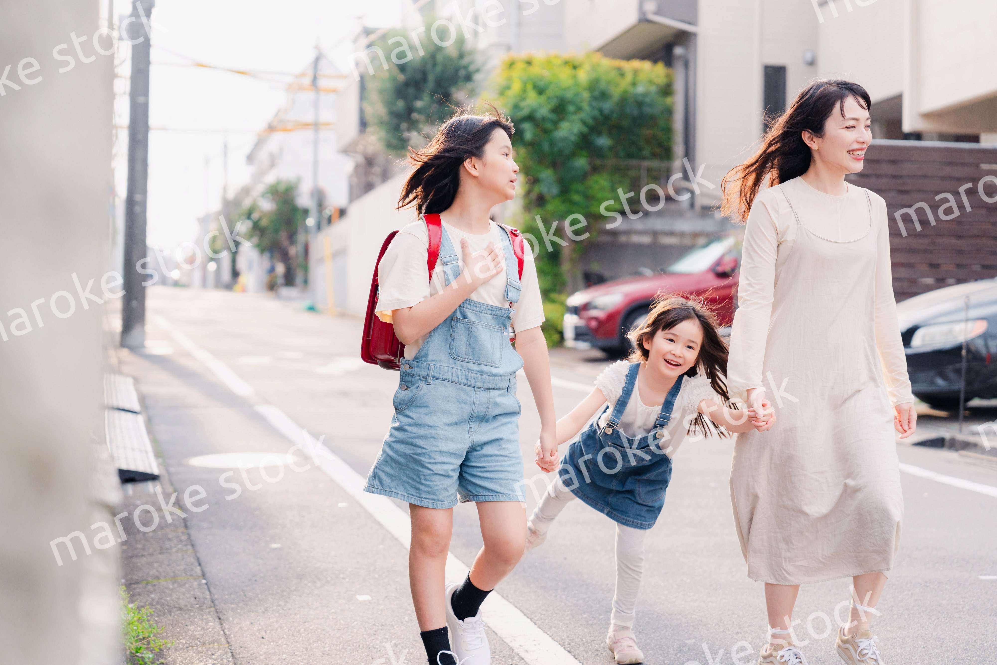 お母さんと手を繋いで学校に行く2人の女の子