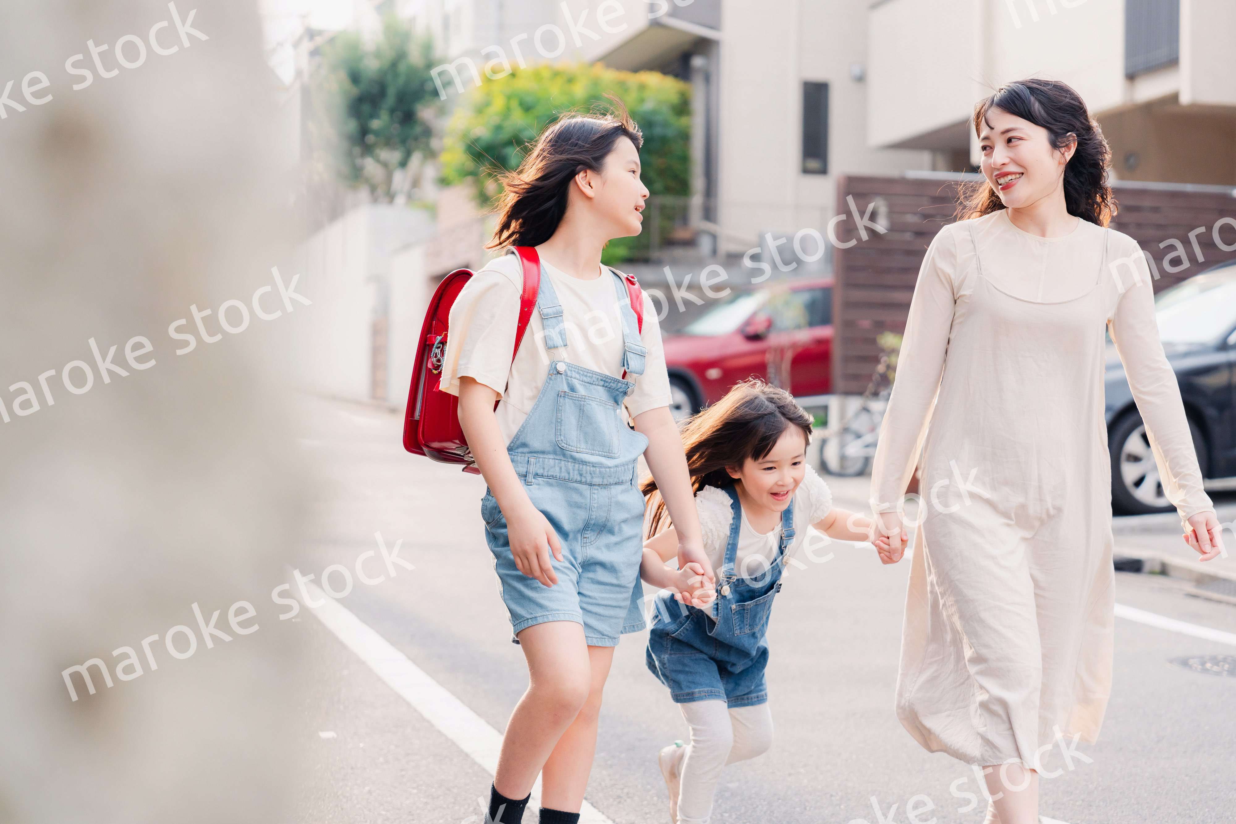 お母さんと手を繋いで学校に行く2人の女の子