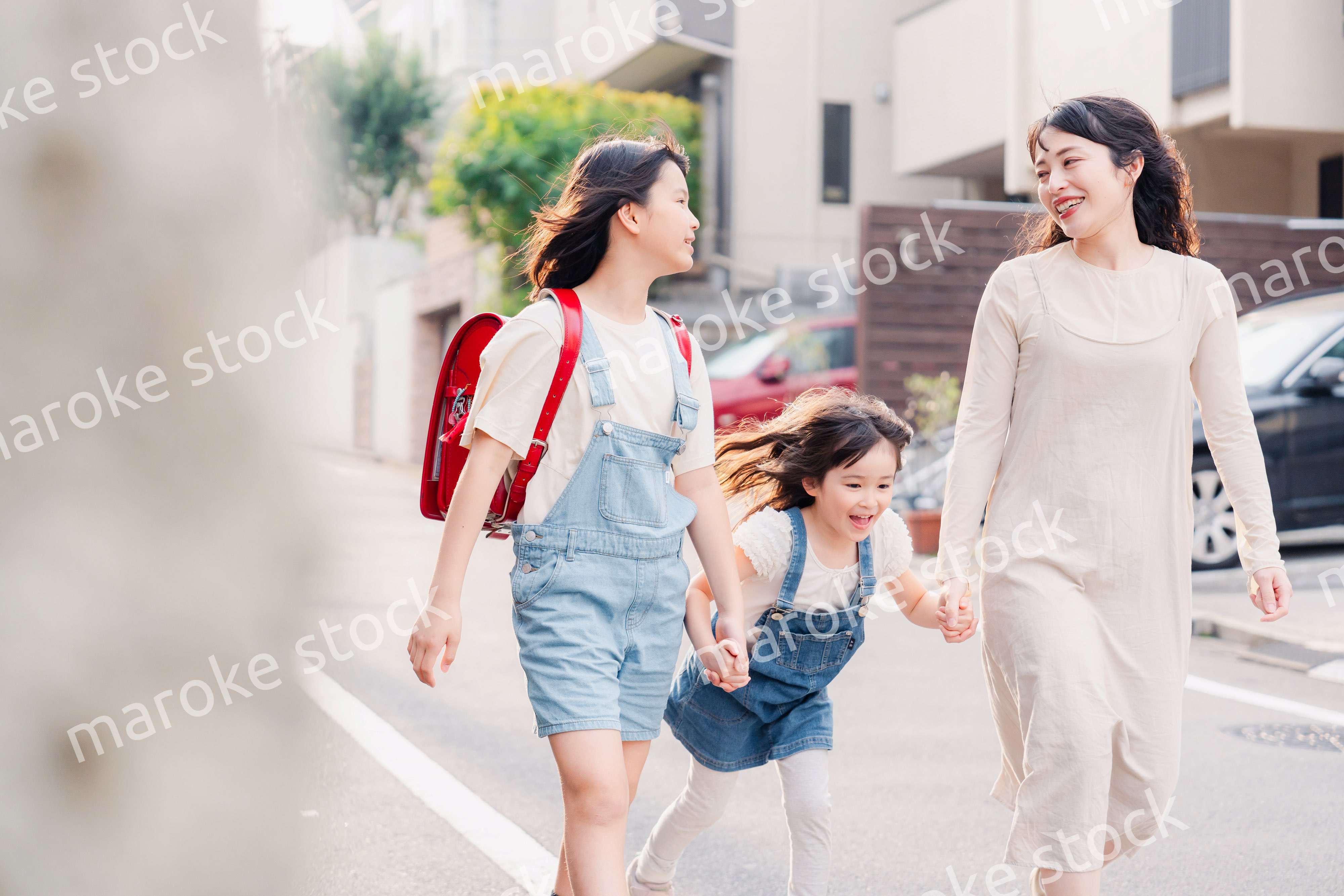 お母さんと手を繋いで学校に行く2人の女の子