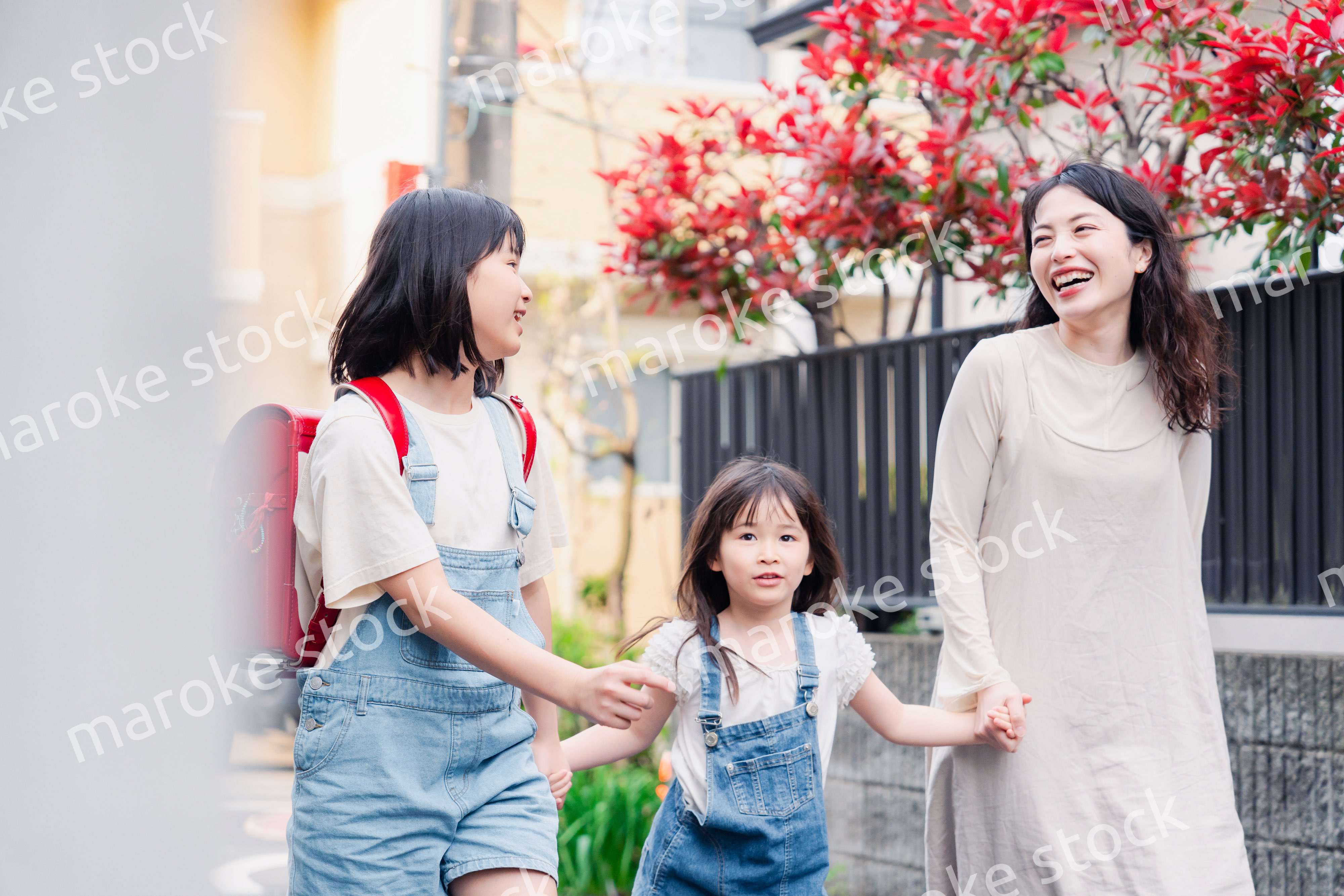 お母さんと手を繋いで学校に行く2人の女の子