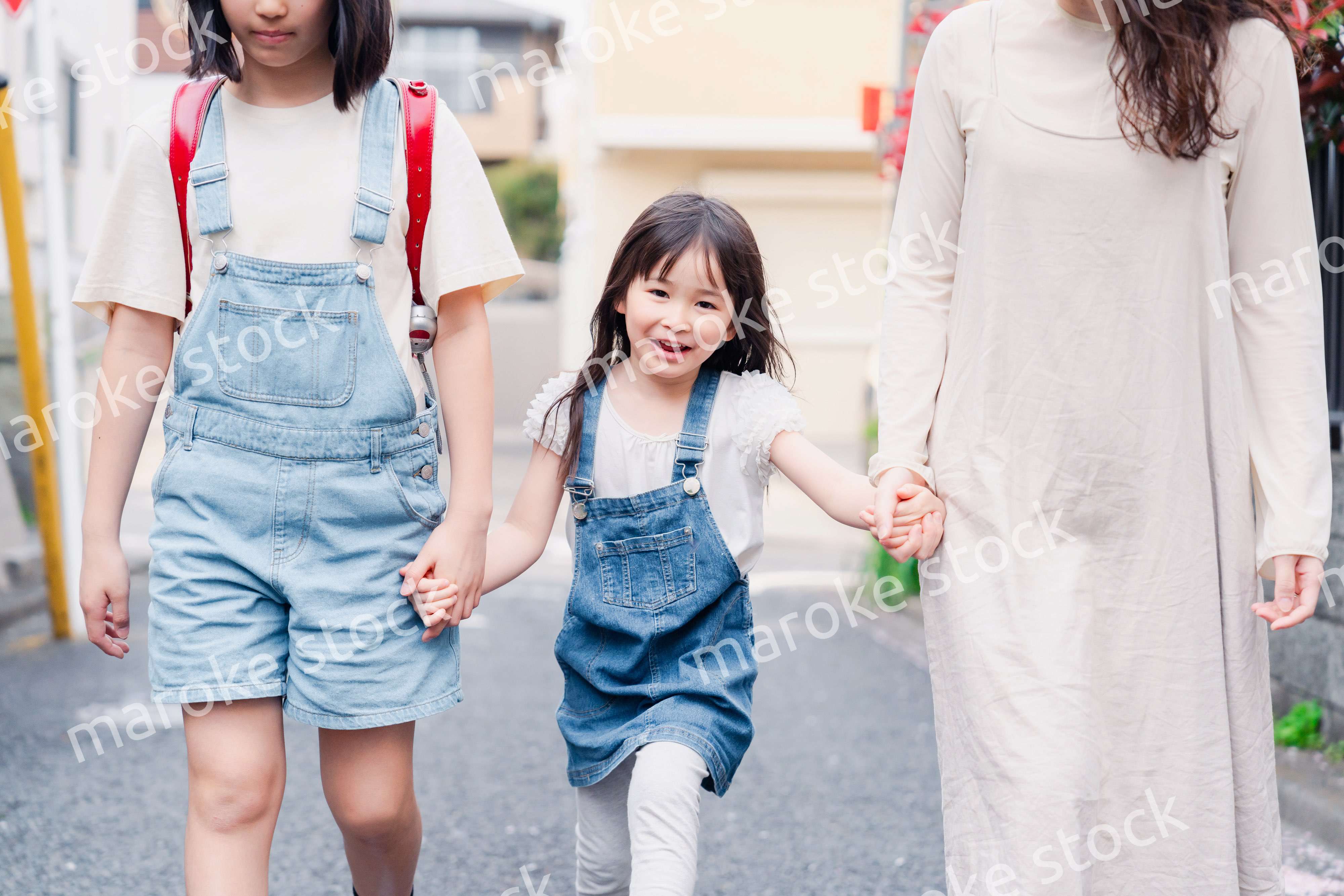 お母さんと手を繋いで学校に行く2人の女の子