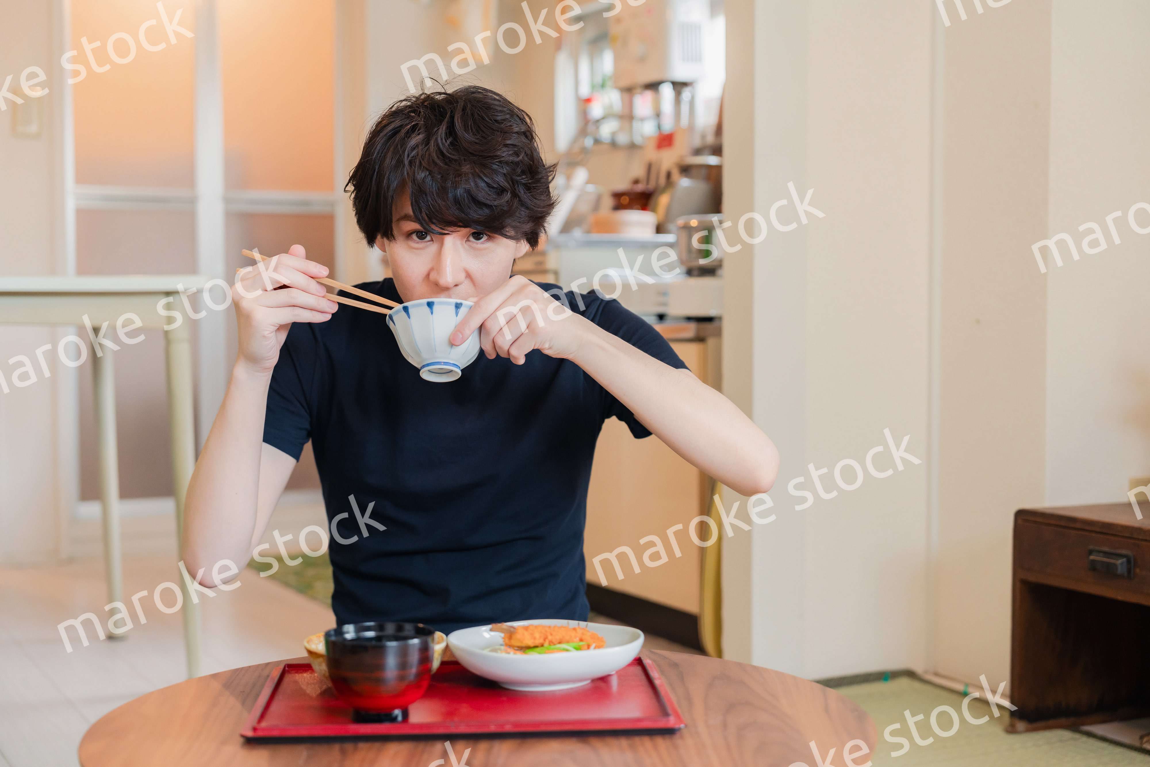 一人暮らしの下宿先でごはんを食べる若い男性