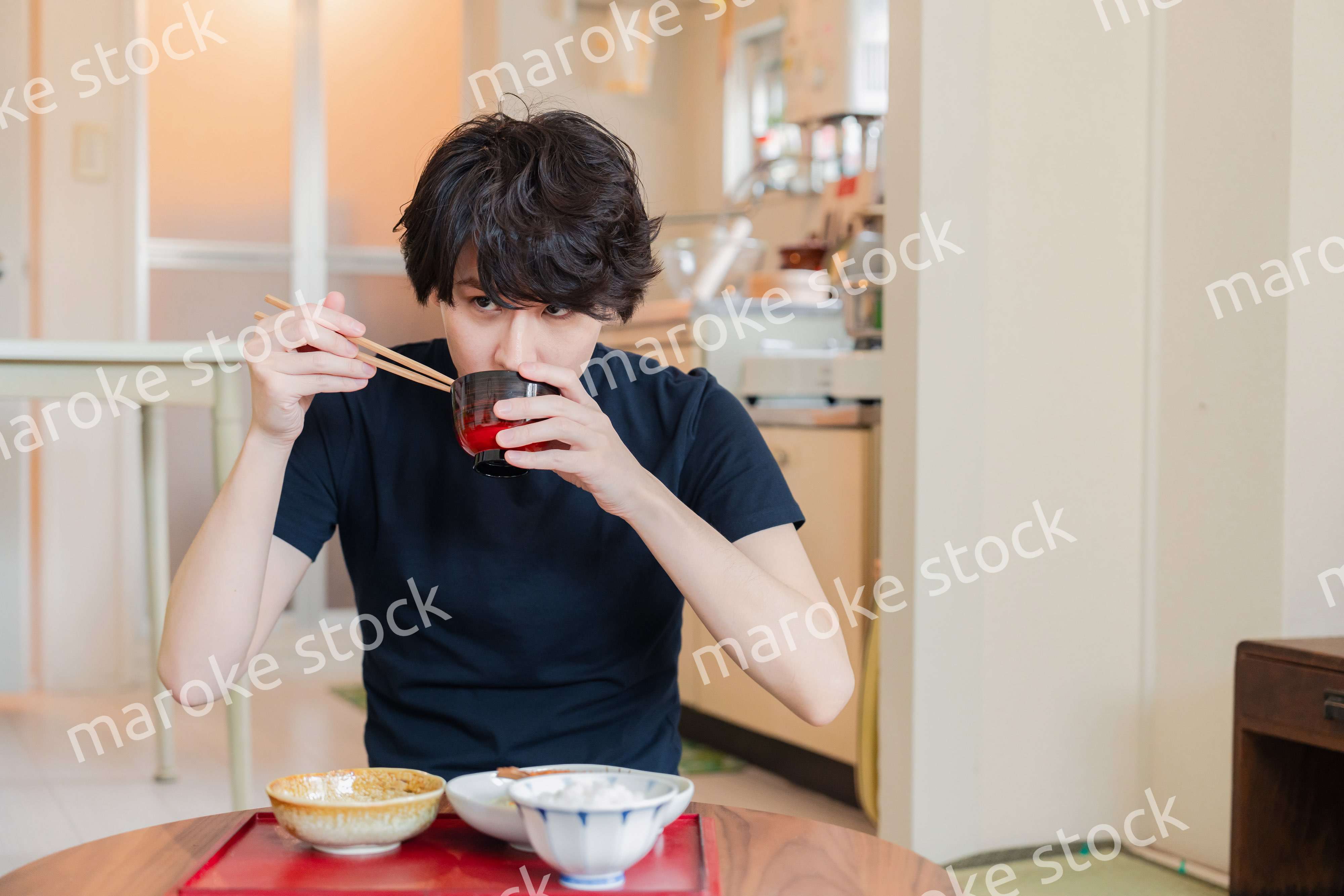 一人暮らしの下宿先でごはんを食べる若い男性