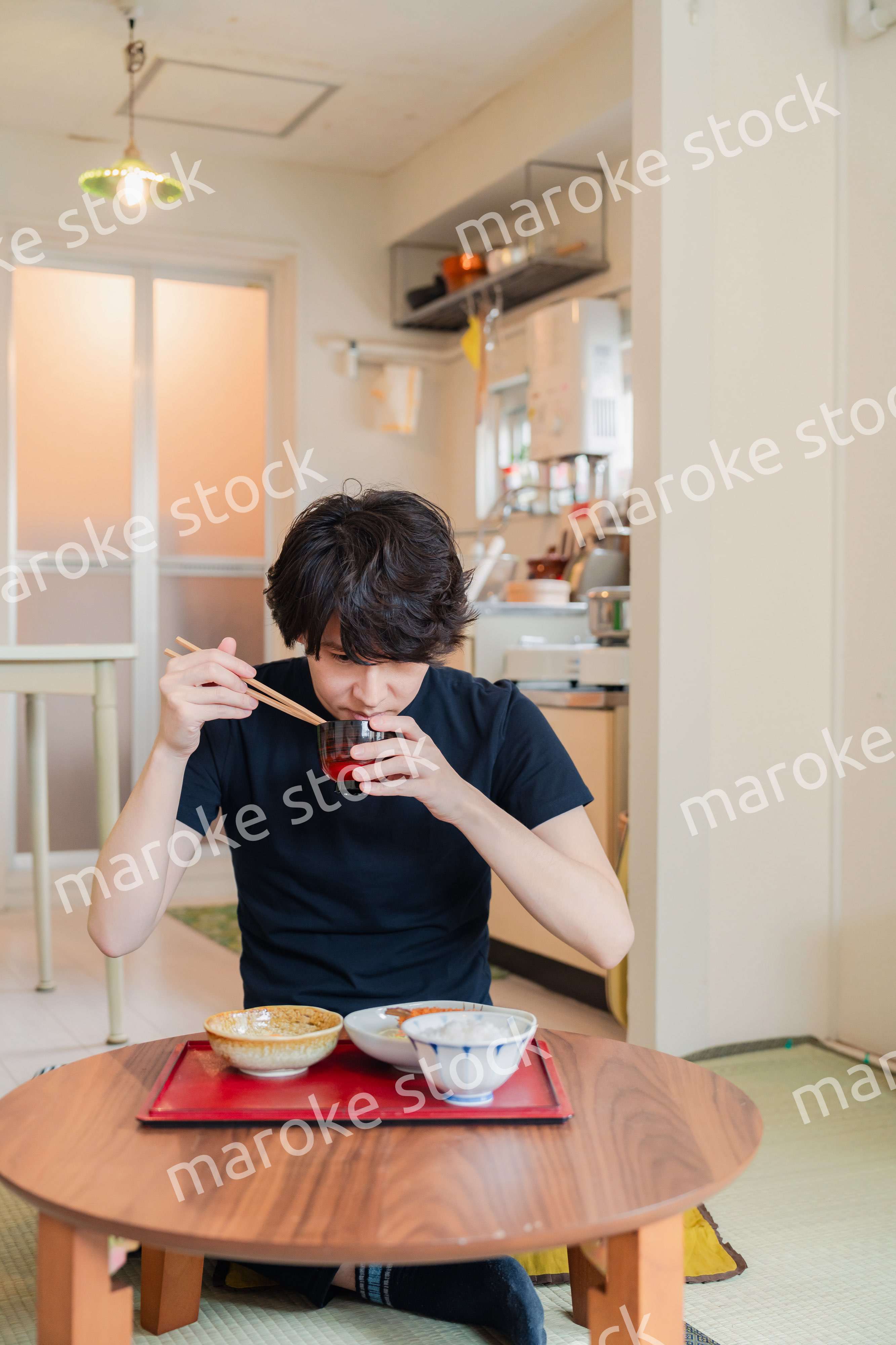 一人暮らしの下宿先でごはんを食べる若い男性