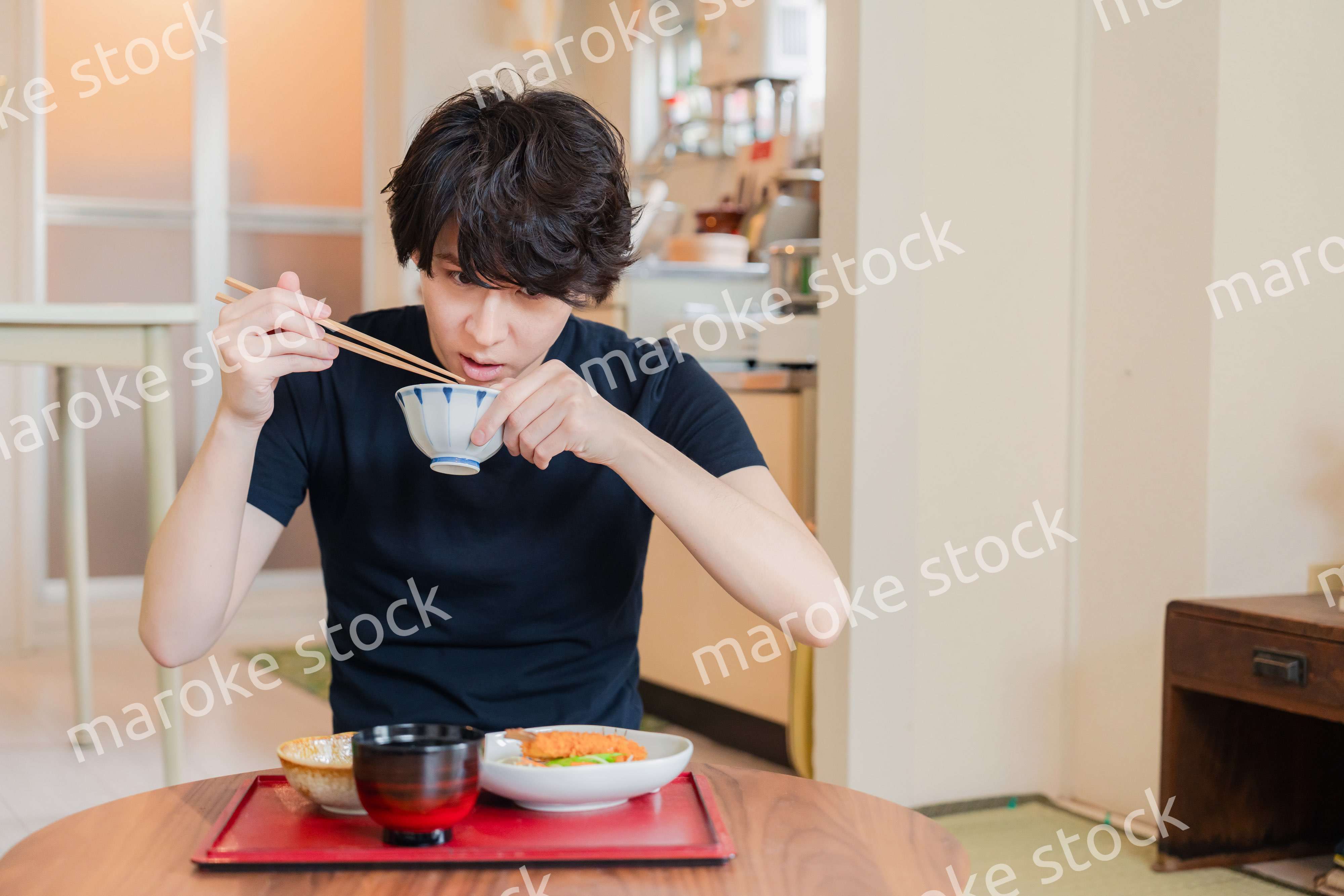 一人暮らしの下宿先でごはんを食べる若い男性