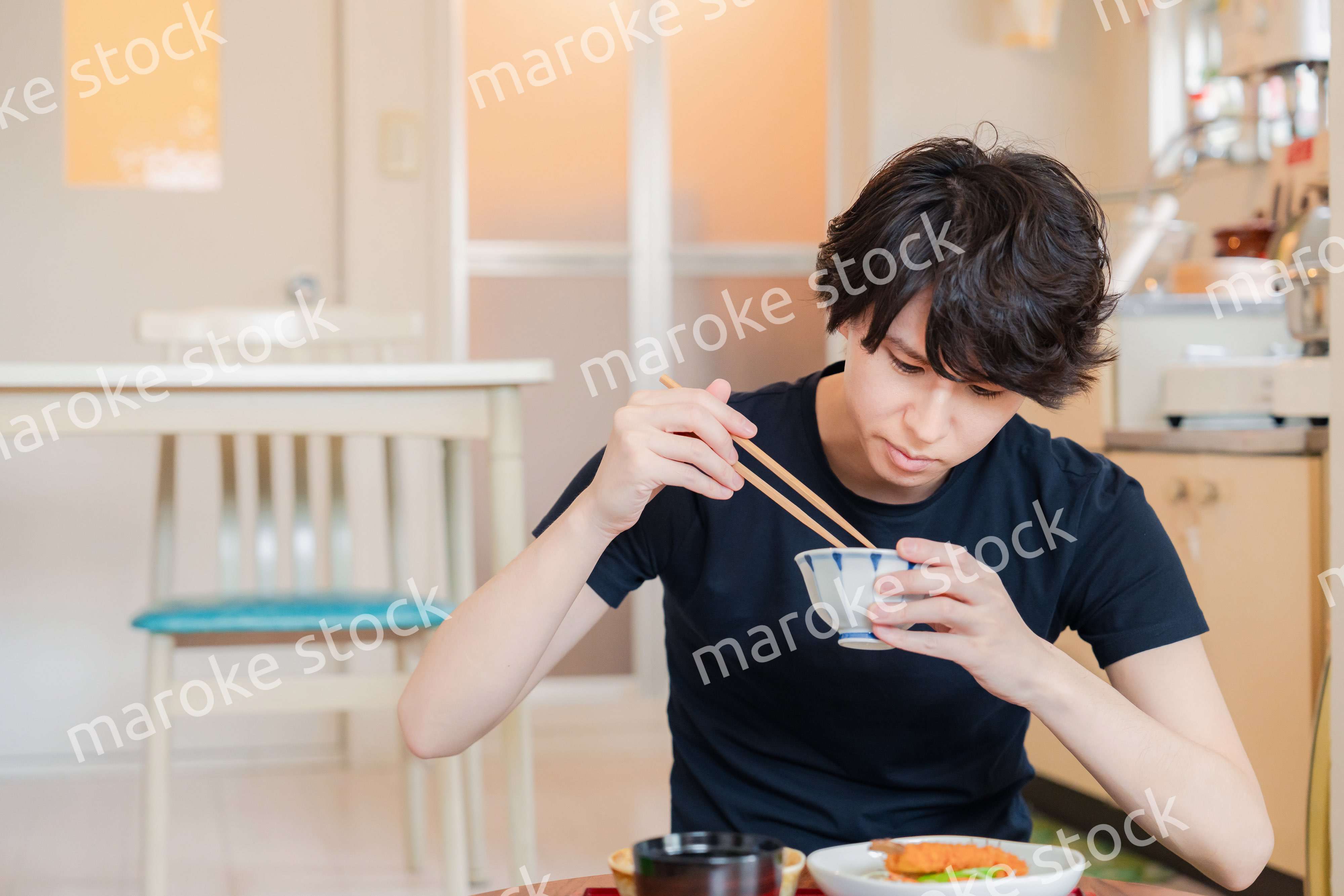 一人暮らしの下宿先でごはんを食べる若い男性