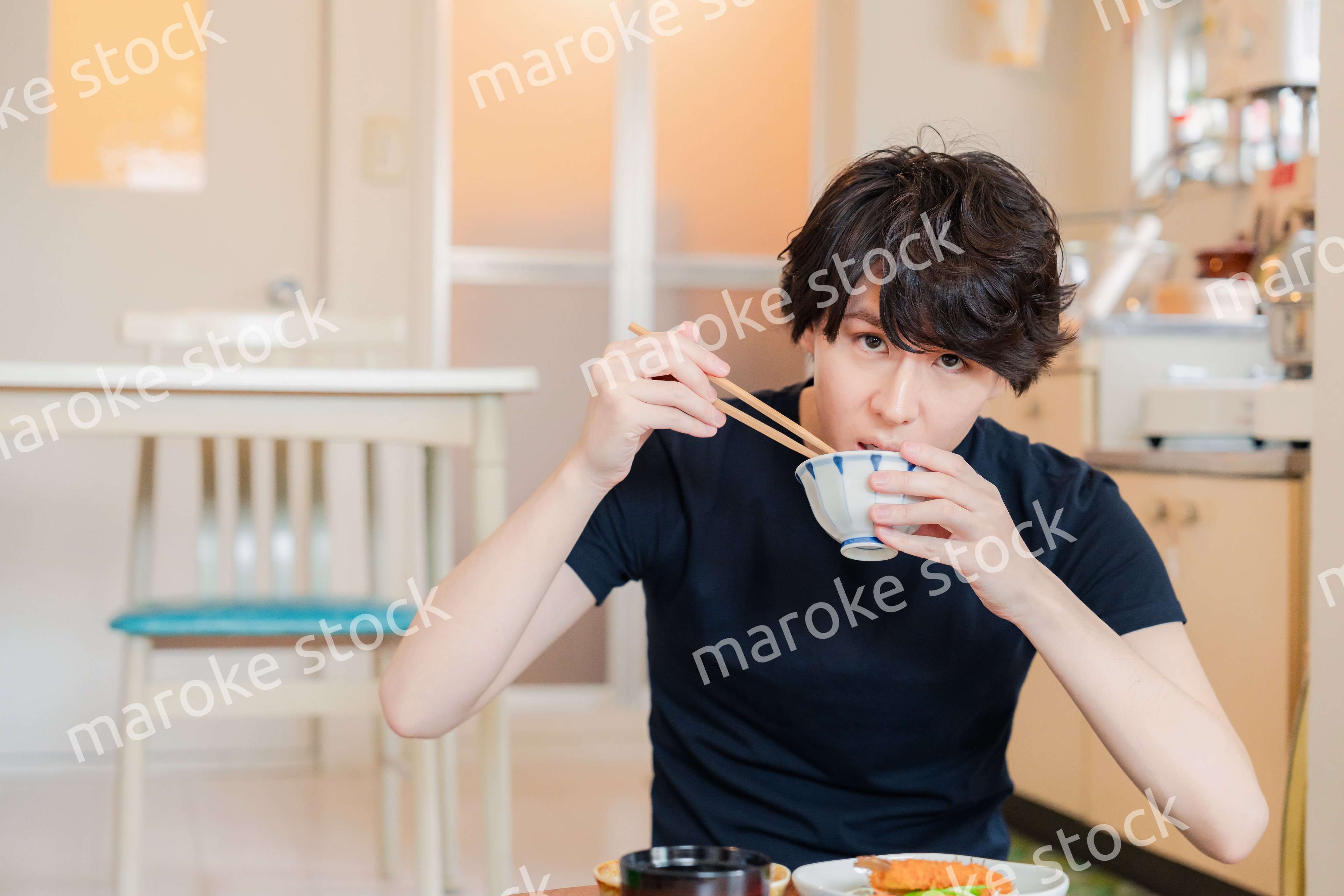 一人暮らしの下宿先でごはんを食べる若い男性