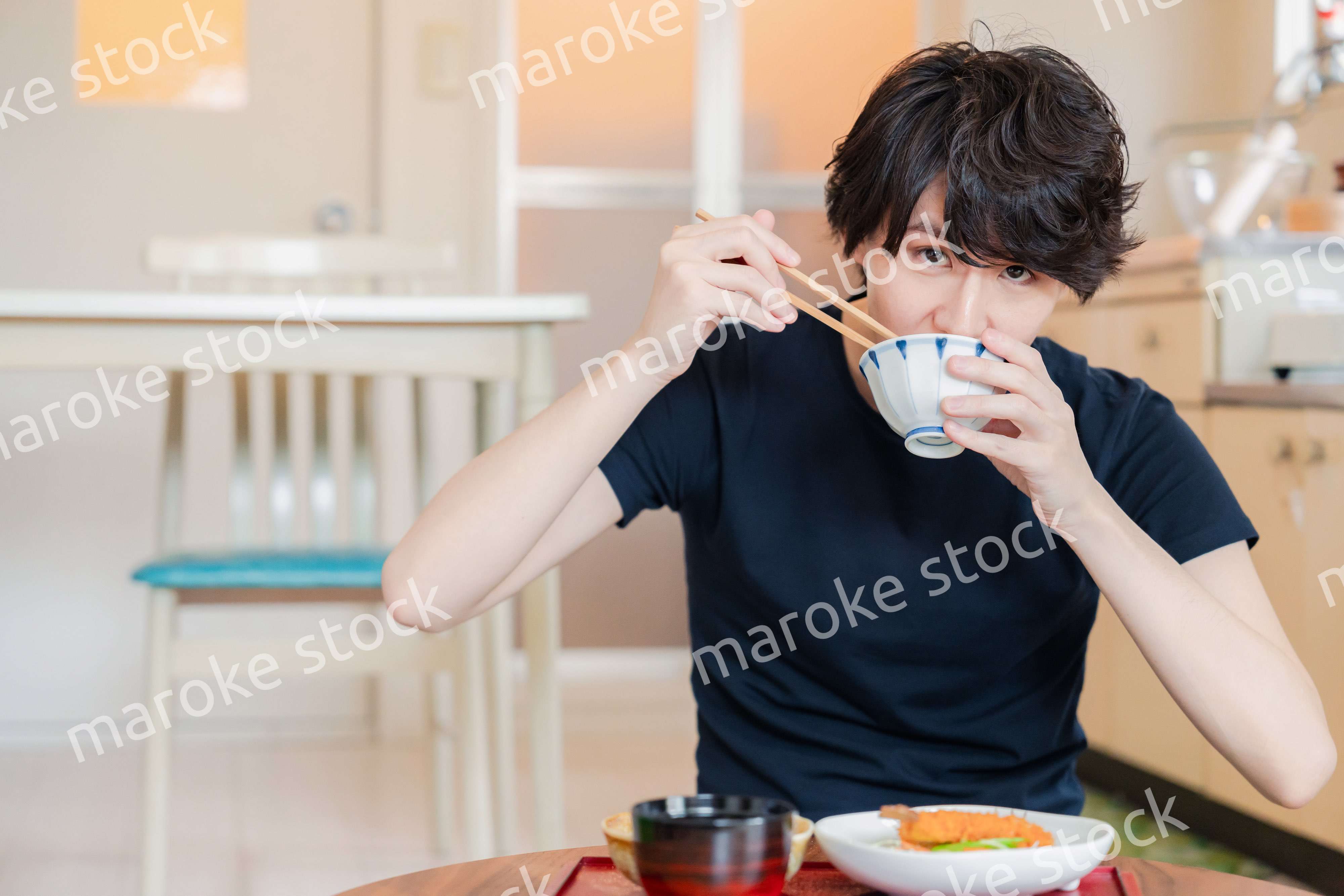 一人暮らしの下宿先でごはんを食べる若い男性