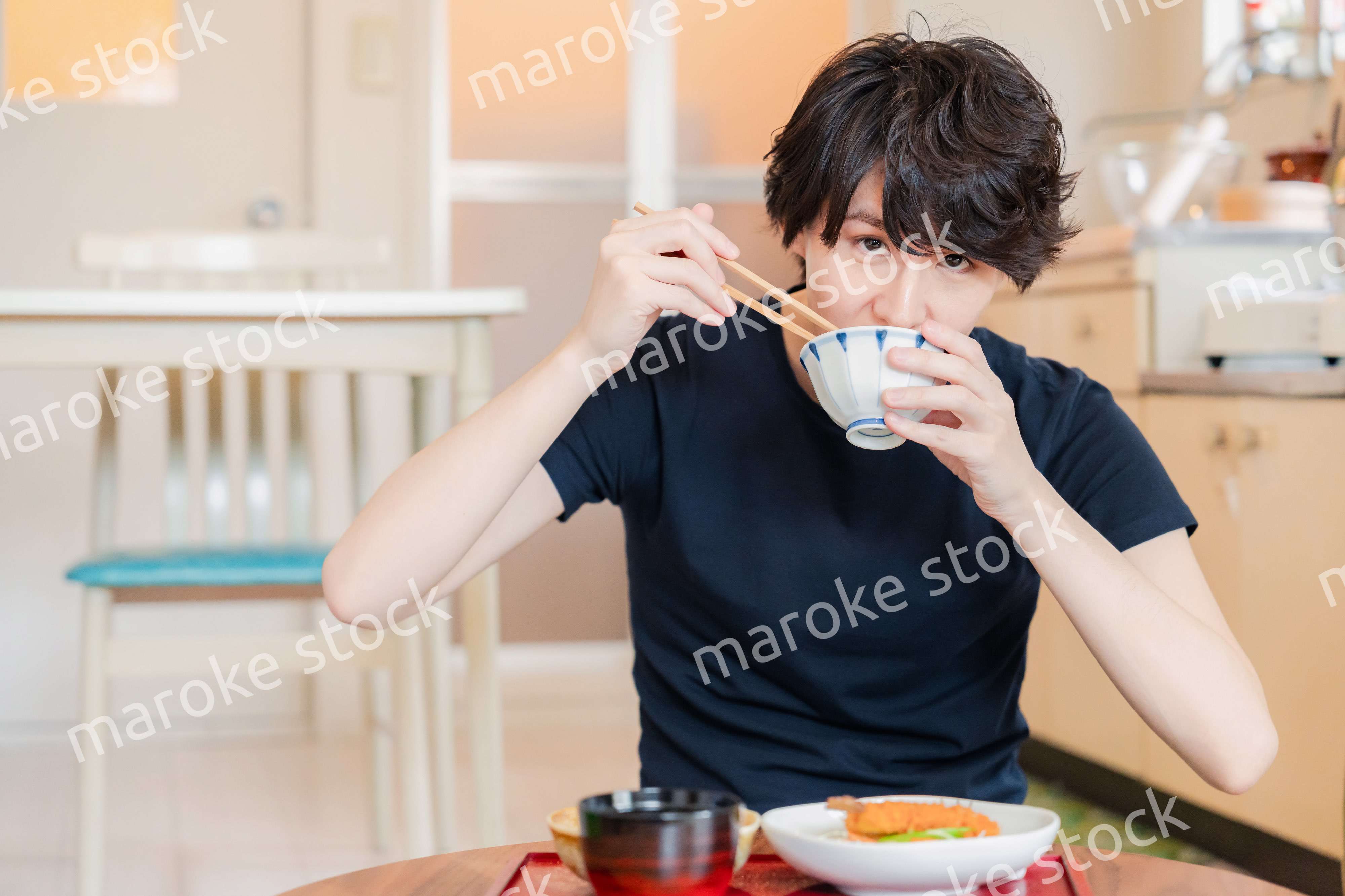 一人暮らしの下宿先でごはんを食べる若い男性