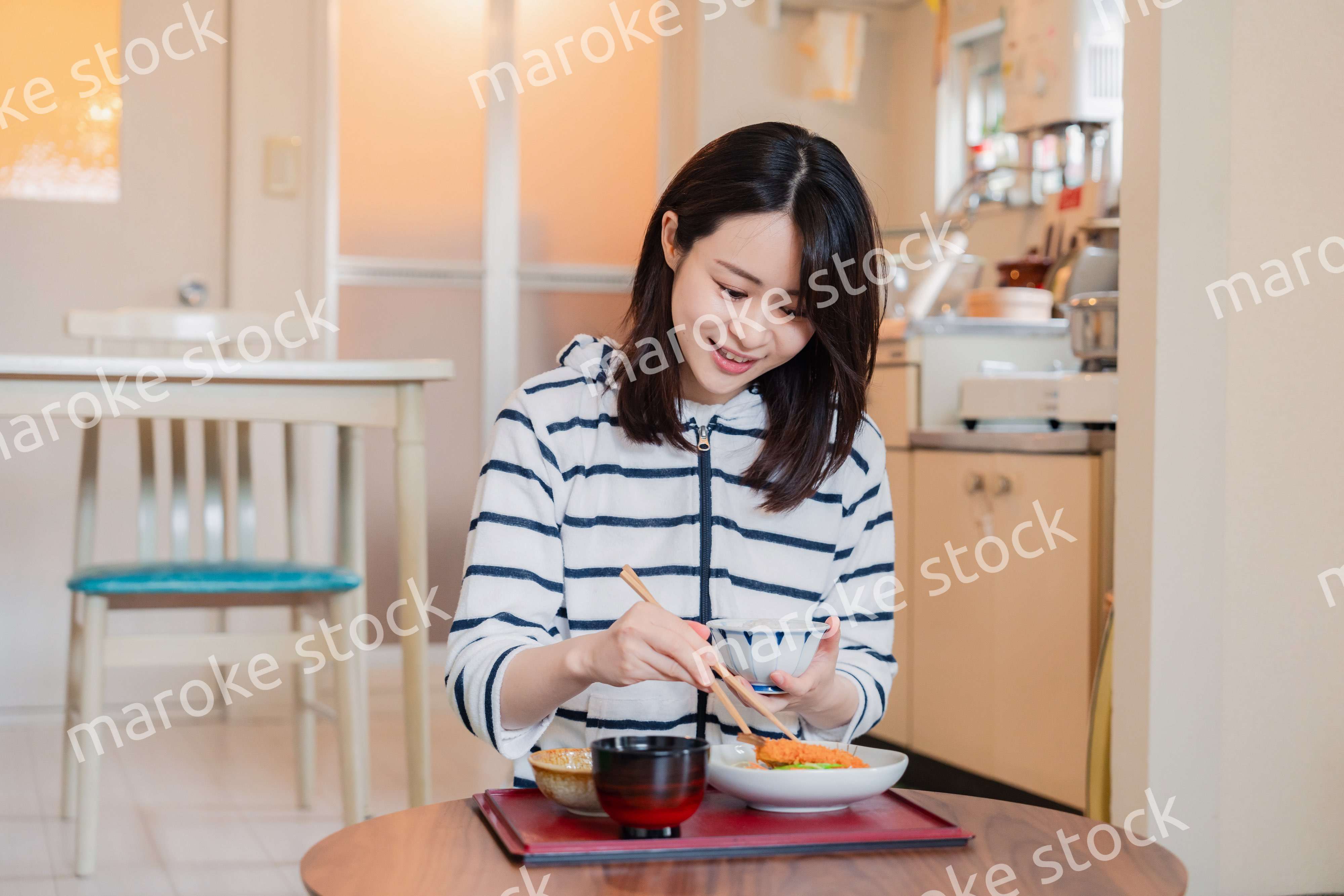 質素な家でごはんを食べる一人暮らしの女性