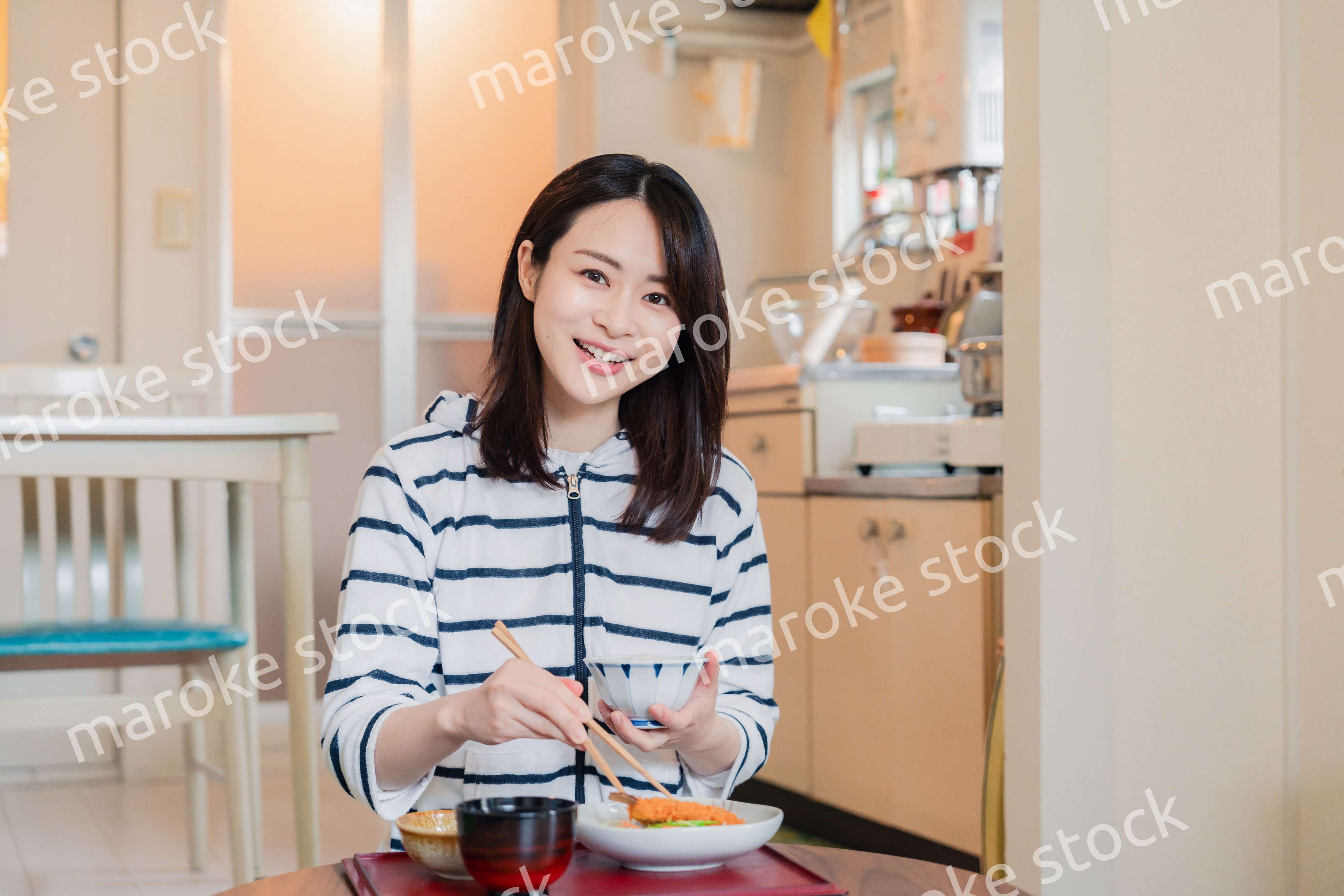 質素な家でごはんを食べる一人暮らしの女性