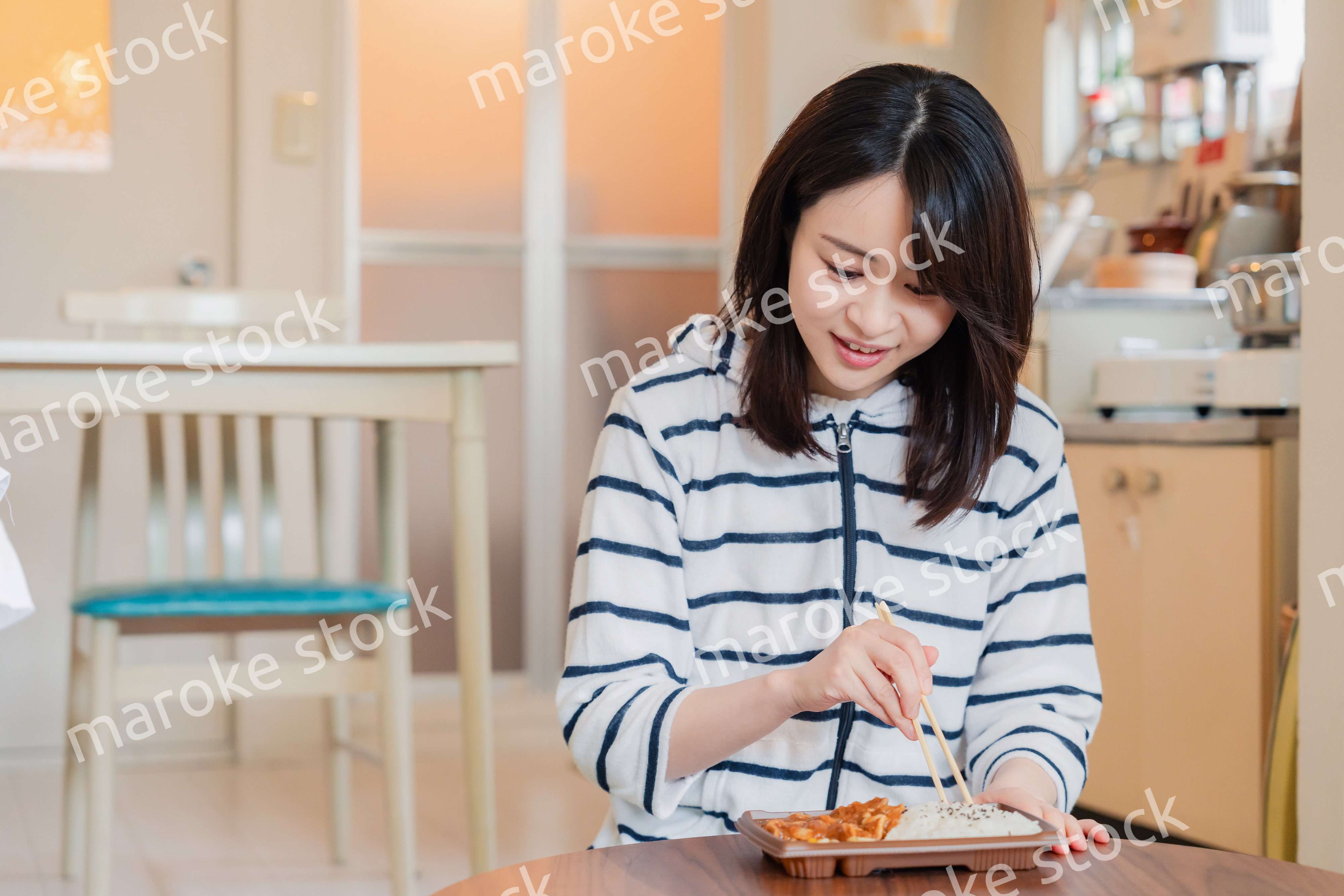 家でひとりでコンビニ弁当を食べる若い女性