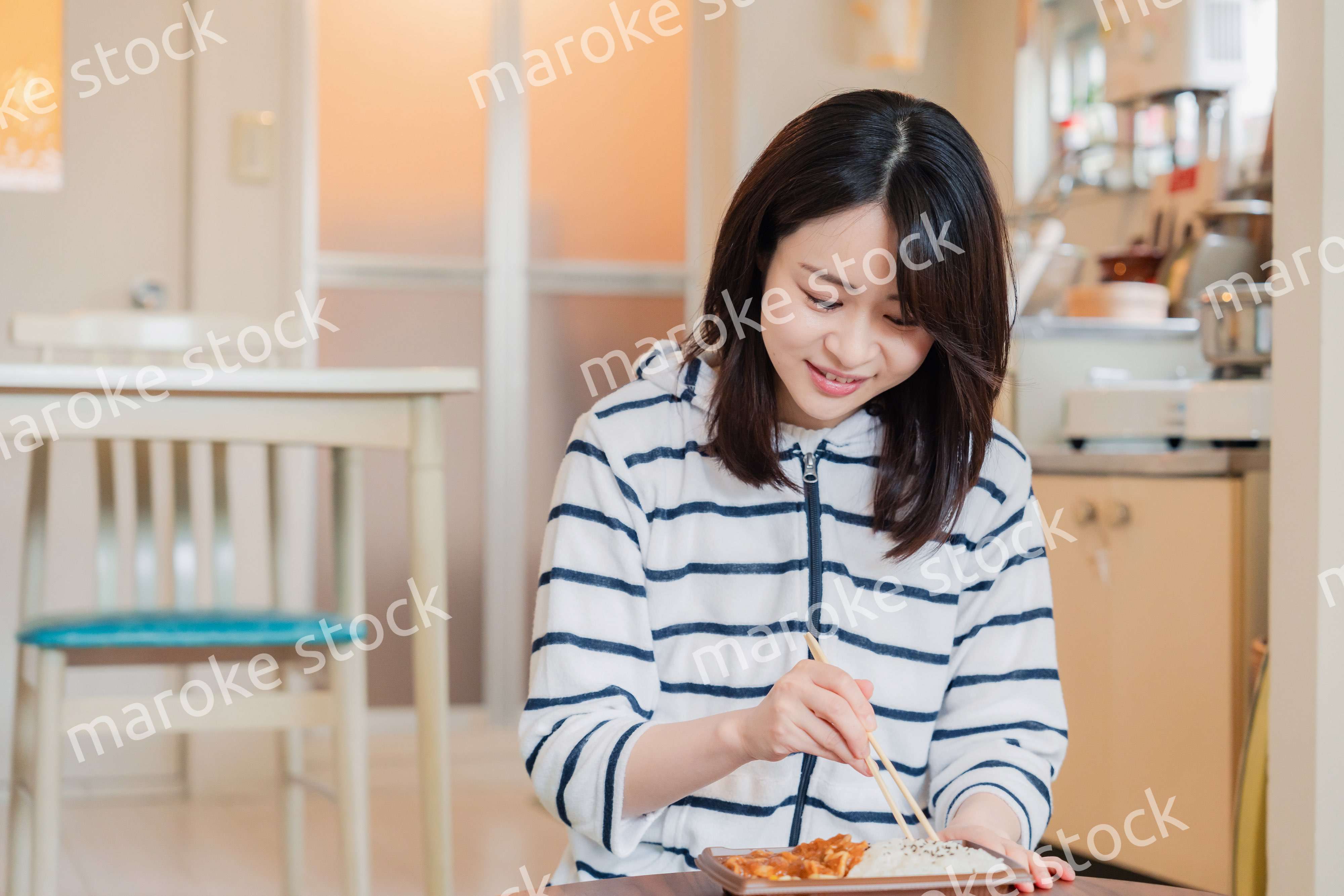 家でひとりでコンビニ弁当を食べる若い女性