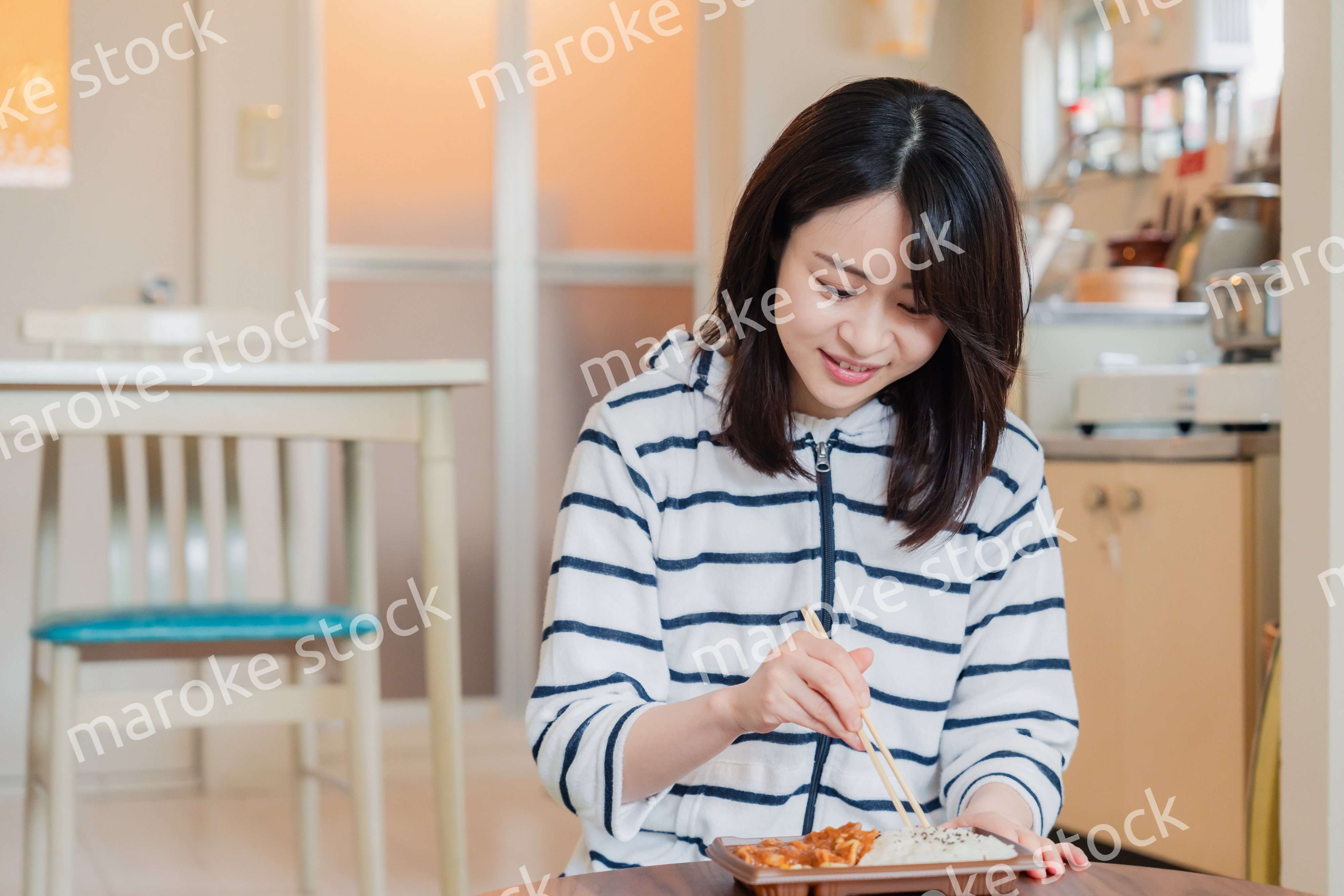 家でひとりでコンビニ弁当を食べる若い女性
