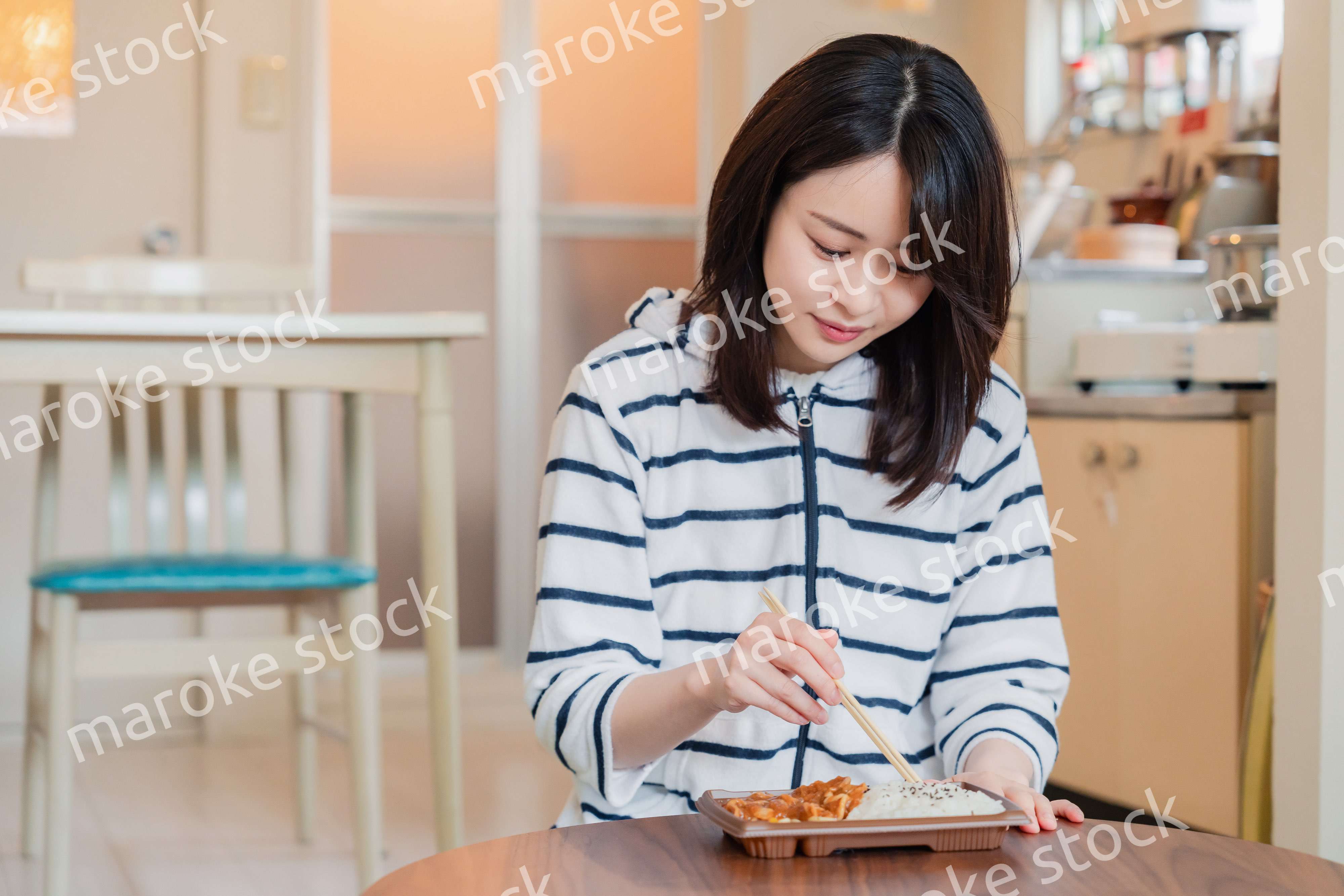 家でひとりでコンビニ弁当を食べる若い女性