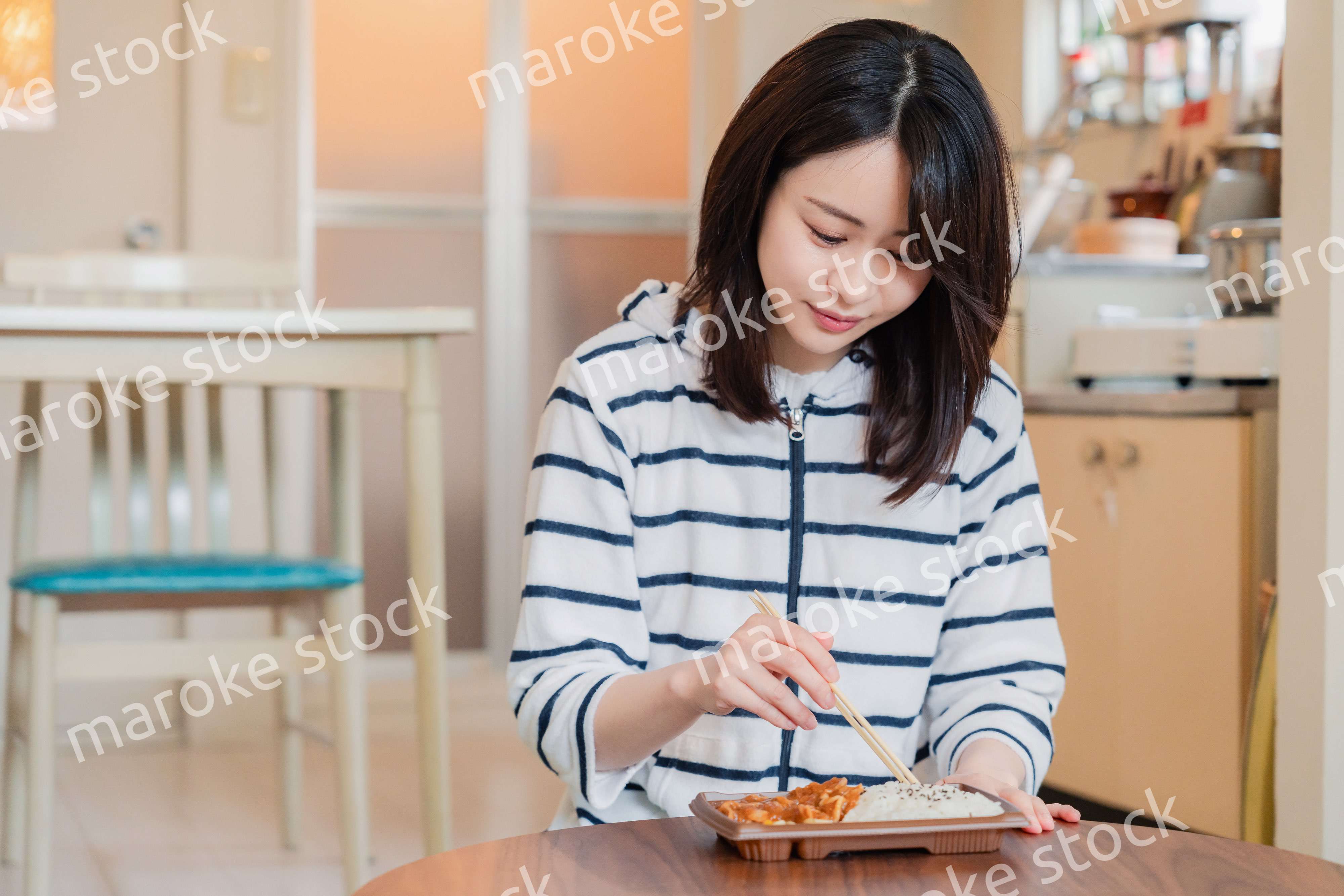 家でひとりでコンビニ弁当を食べる若い女性