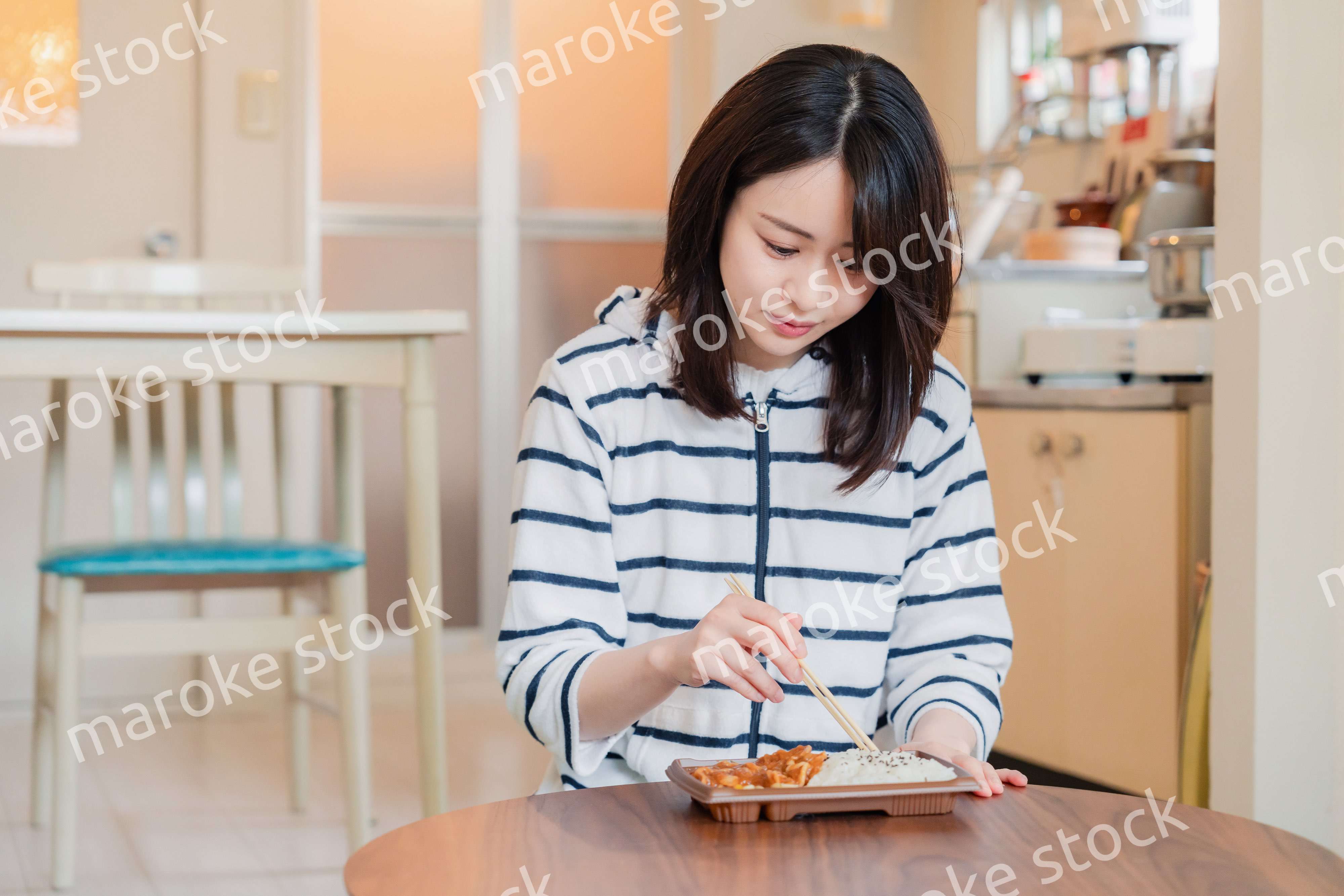 家でひとりでコンビニ弁当を食べる若い女性