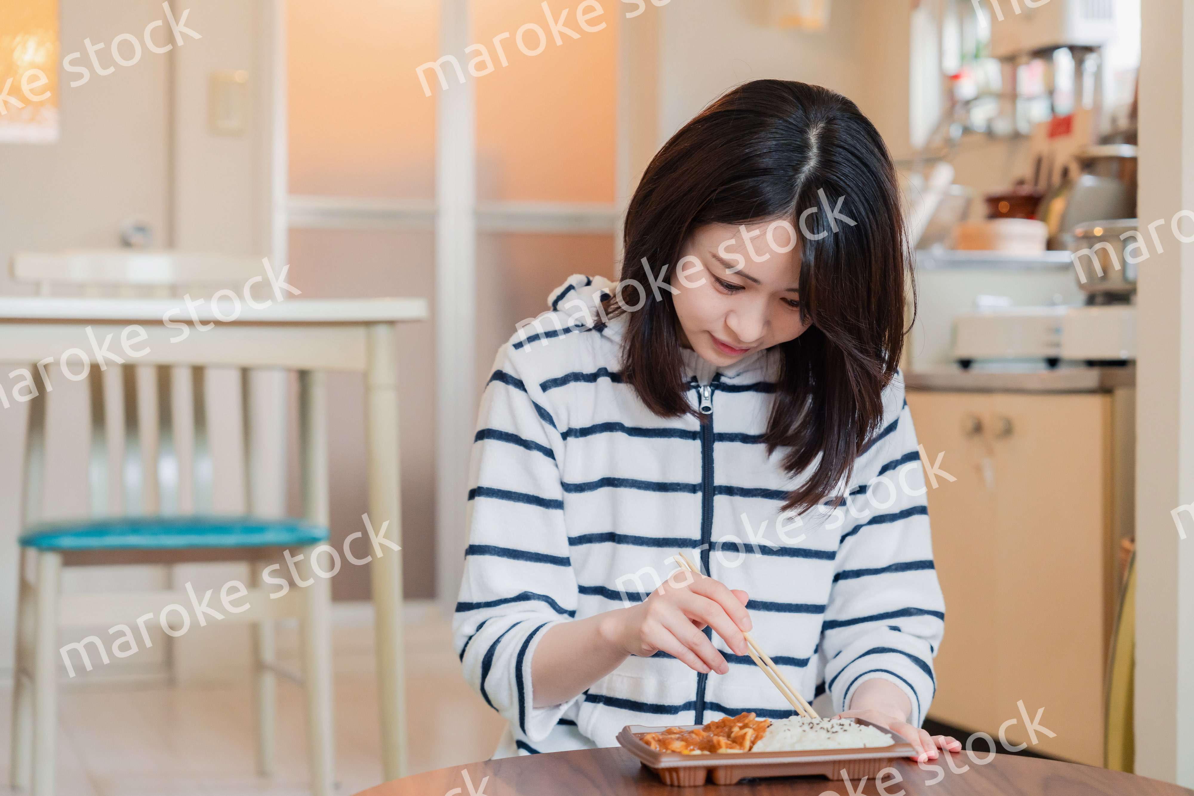 家でひとりでコンビニ弁当を食べる若い女性